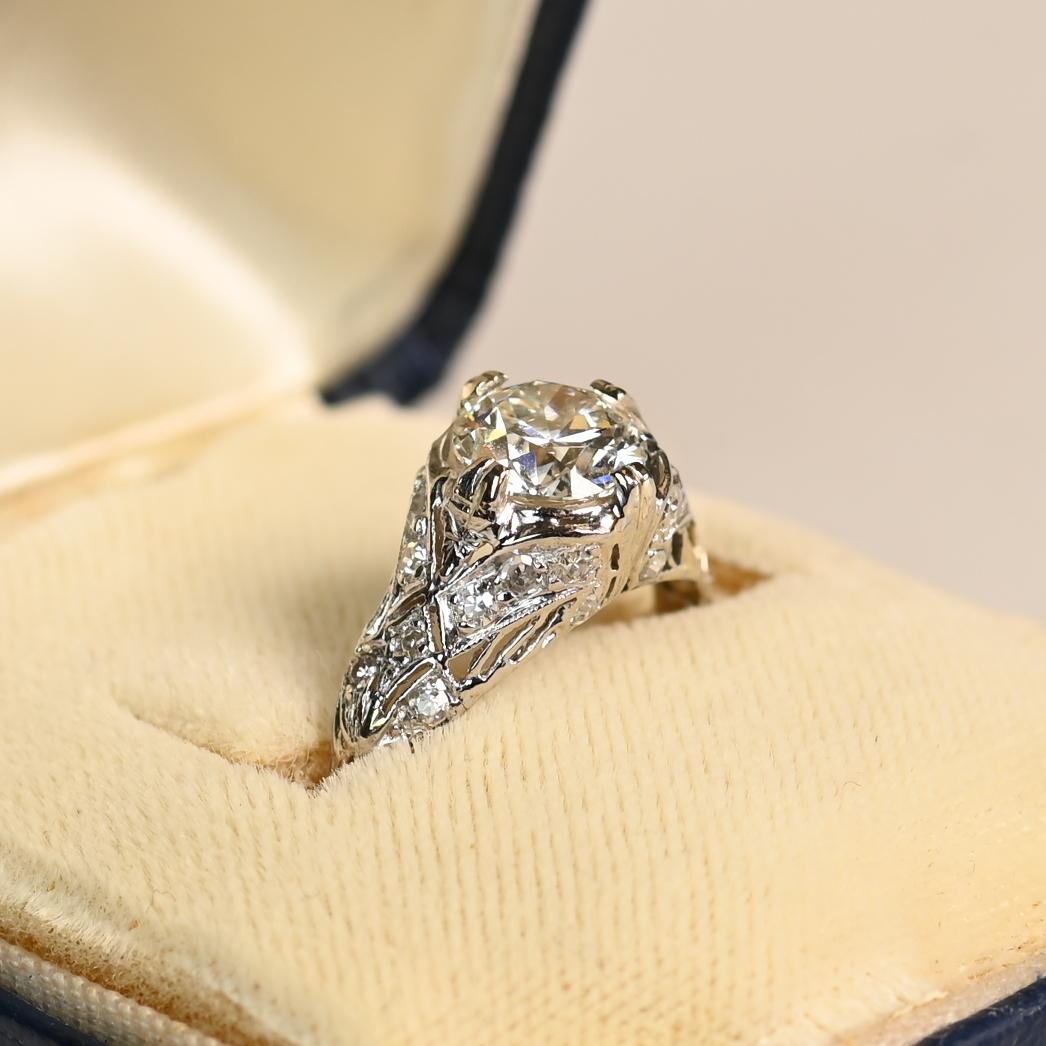 Este exquisito Anillo de Compromiso Art Dec�ó Antiguo, de hacia 1925, exhibe un cautivador diamante de talla europea antigua de aprox. 1,2 quilates, clasificado J en color y VS1 en claridad. El diamante está engarzado con seguridad en delicadas