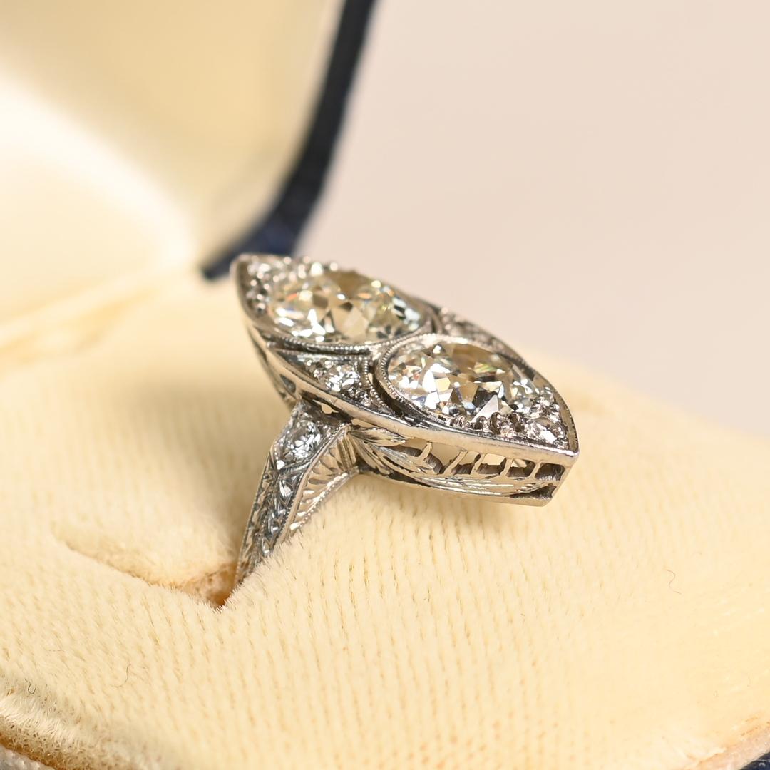Este exquisito anillo navette de la época Art Decó exhibe dos deslumbrantes diamantes de talla europea antigua, cada uno con un peso aproximado de 1,20 quilates. De color J y claridad VS2, estos diamantes antiguos irradian un brillo cautivador.