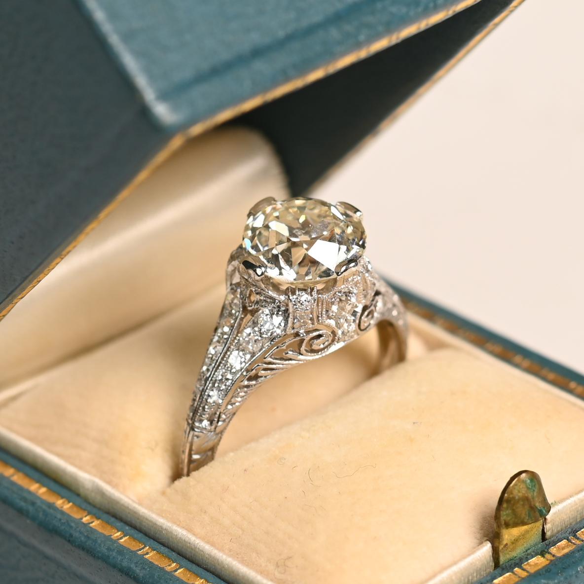 This exquisite antique engagement ring showcases a breathtaking approx 2.50-carat old European cut diamond, graded L in color and SI2 in clarity. Set securely in elegant prongs, the center stone radiates a timeless charm, capturing the romance of a