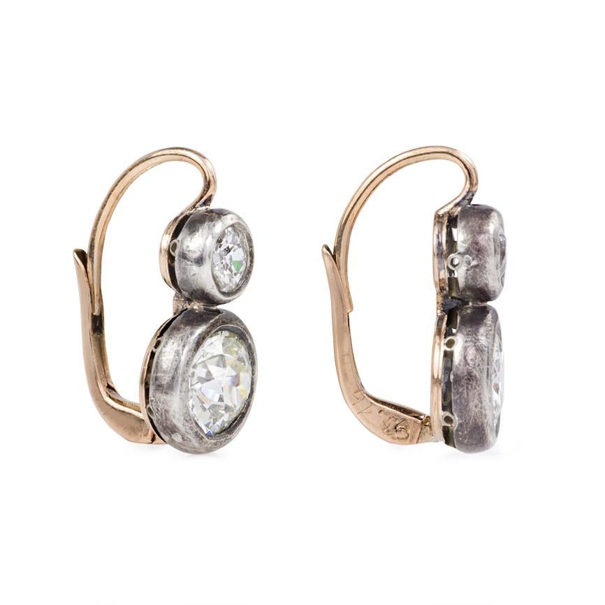 A pair of antique two-stone old European cut diamond dormeuse earrings in collet settings, in 18k gold and sterling silver.  Atw 2.69 ct. diamonds