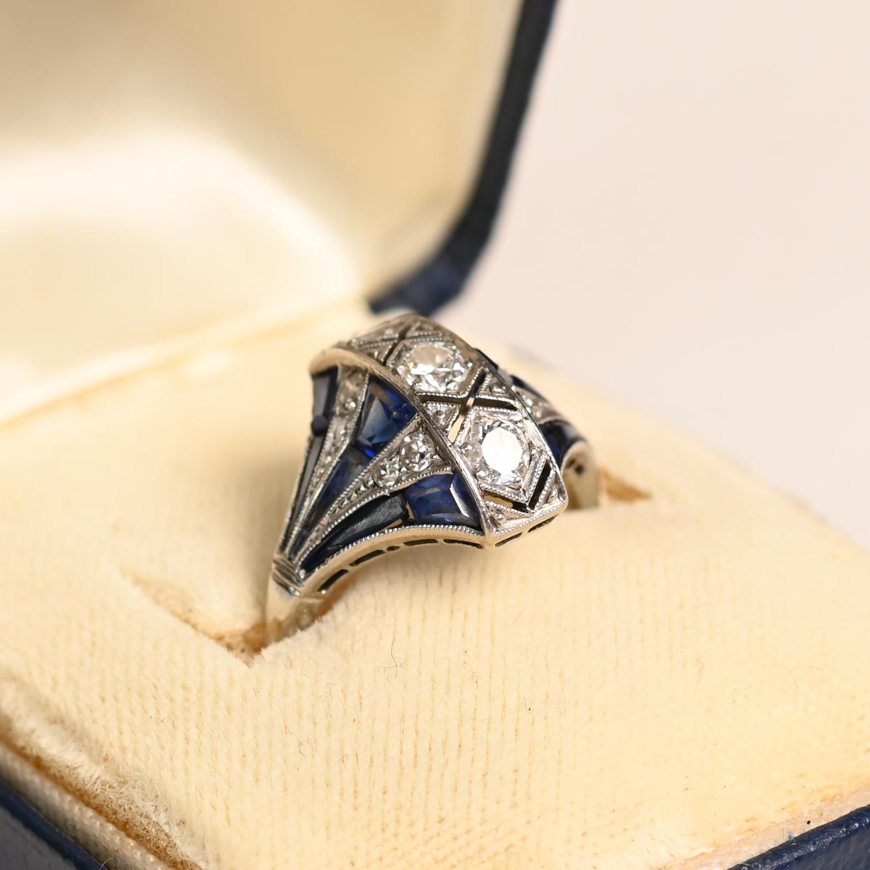 Cette exquise bague de fiançailles ancienne, datant d'environ 1920, est un magnifique exemple de l'art déco. Fabriquée à la main en platine, la bague présente un arrangement vertical sophistiqué de trois diamants de taille européenne ancienne,