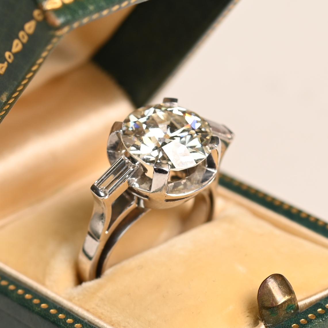Questo squisito anello di fidanzamento mette in mostra un magnifico diamante di taglio europeo antico, incastonato al centro e certificato GIA con circa 4,3 carati, colore K e purezza SI1. Con un'eleganza senza tempo, la pietra centrale mostra il