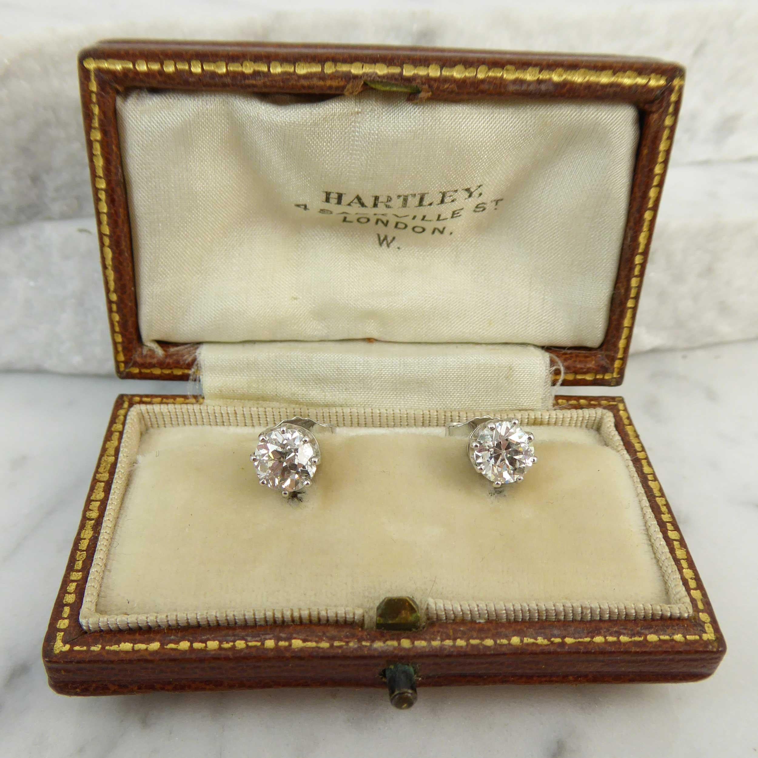 Antique old European cut diamonds form a pair of solitaire diamond stud earrings.  Each diamond is set within a classic white undulating gallery in an eight-prong mount and fitted with post and butterfly fittings for pierced ears.  The diamonds