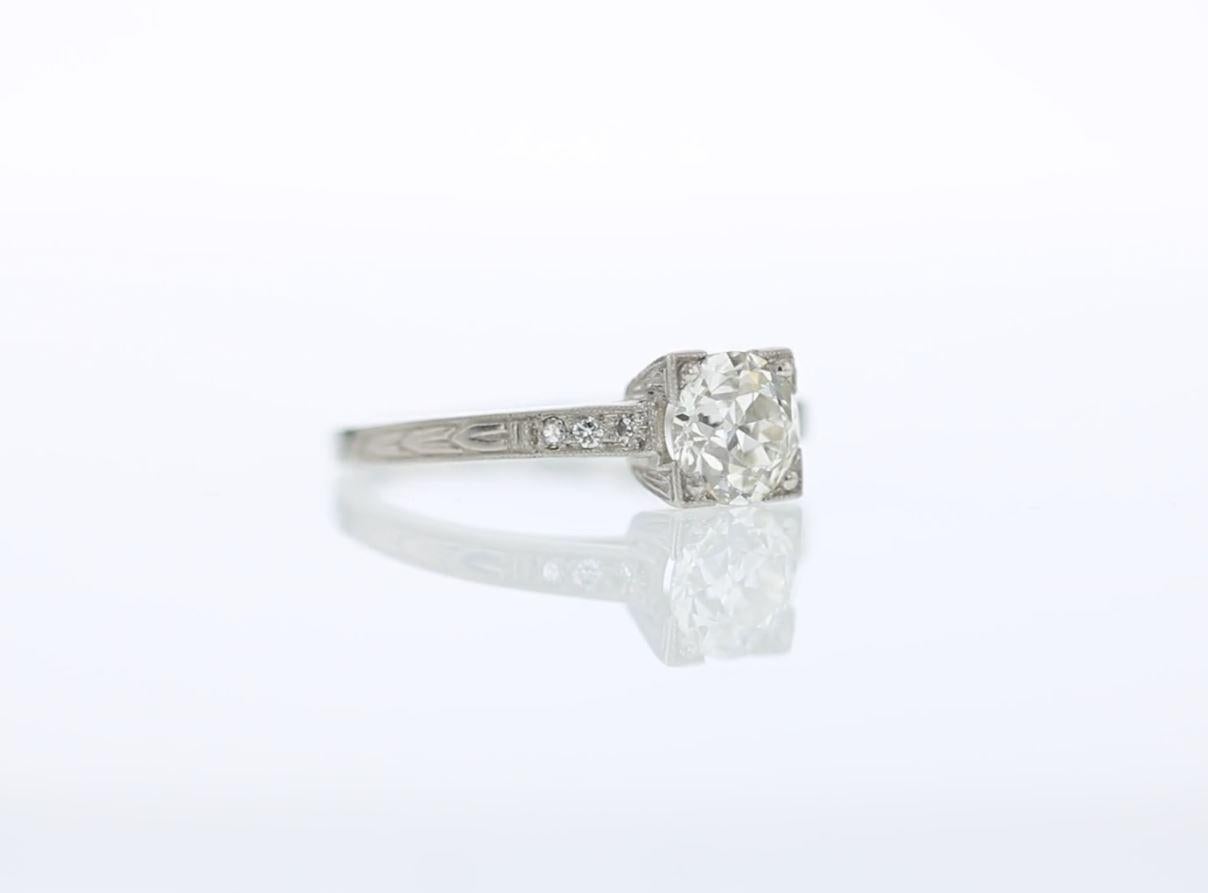 This fine estate engagement ring is centered by a stunning old European diamond of approximately 1.05 carat.  with round diamond accents on either side. The platinum setting features elegant engraving and millegrain work and is set with six