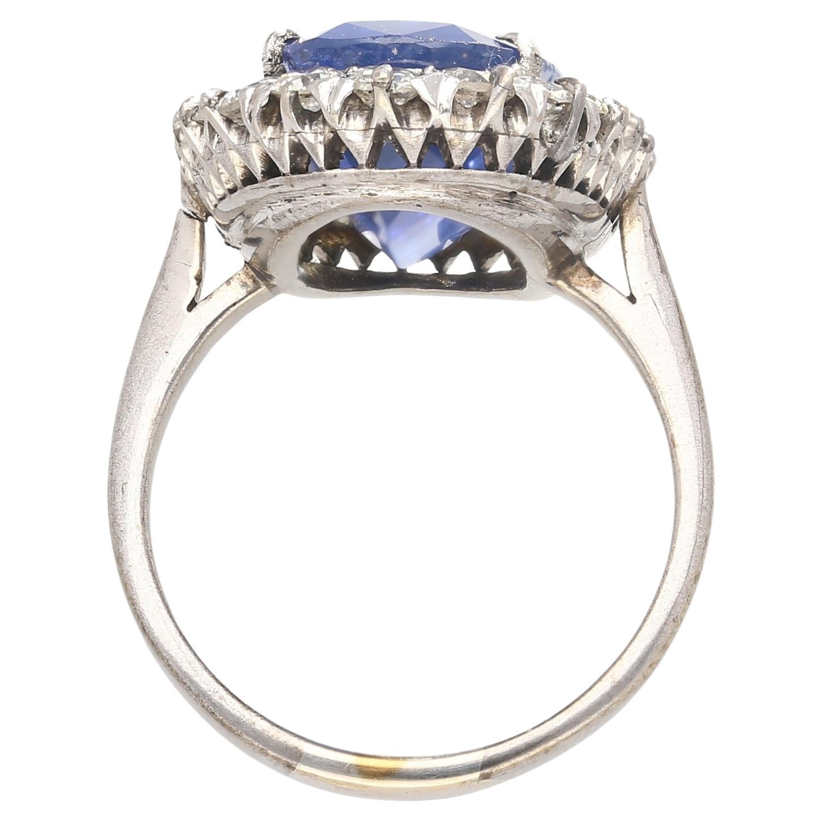 Shop this antique relic from a simpler time. An unheated 11.30-carat oval cut Blue Sapphire of Burmese origin. Set in platinum with a round-cut diamond halo. GRS certified with origin report. Circa late 1800's. The sapphire's natural inclusions,