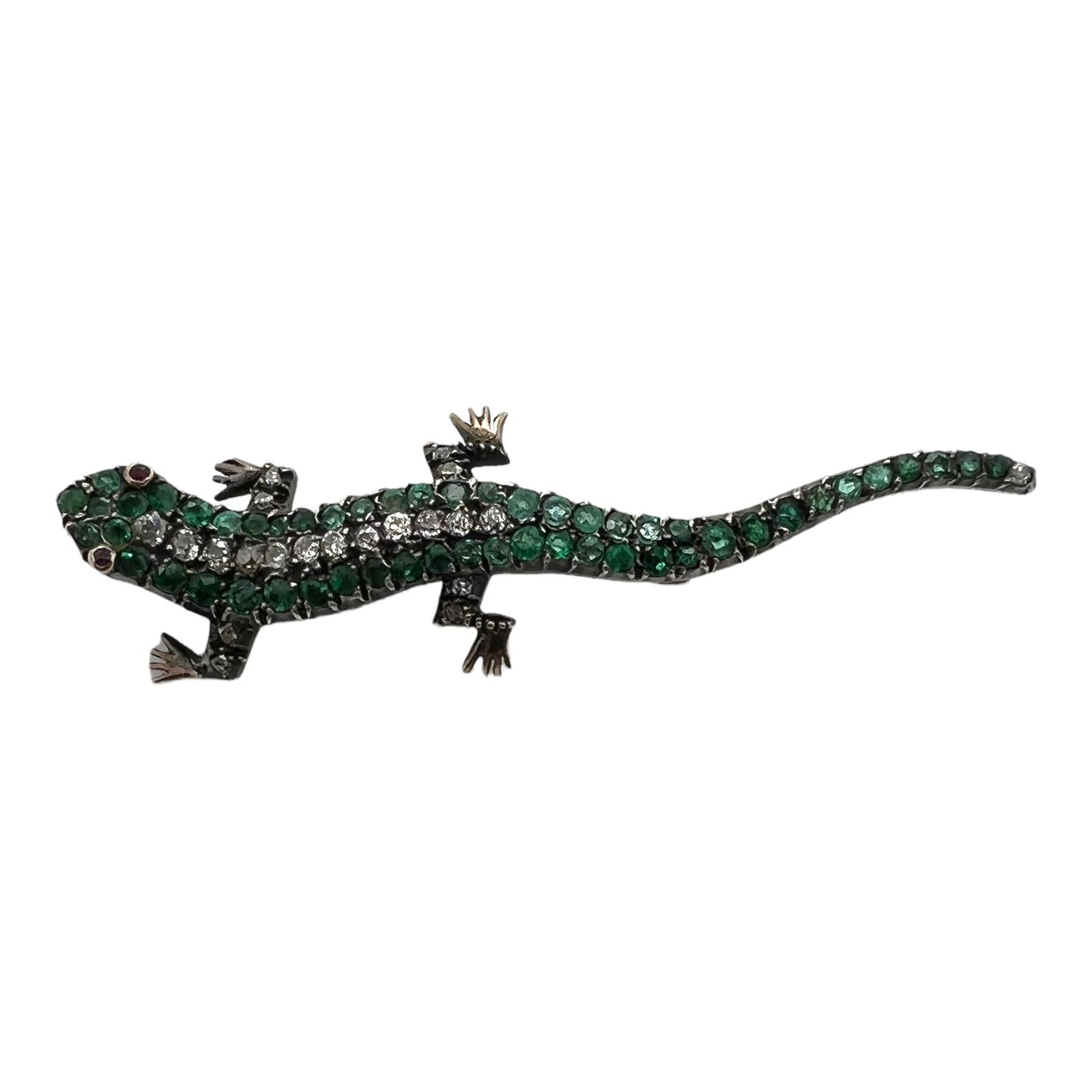 Fabulous Antique Diamond Emerald Salamander Brooch handcrafted in 14 karat yellow gold and sterling silver. The brooch features 13 Old Mine and Old European cut diamonds weighing approximately .25 CTW and 51 natural emeralds. The eyes are set with