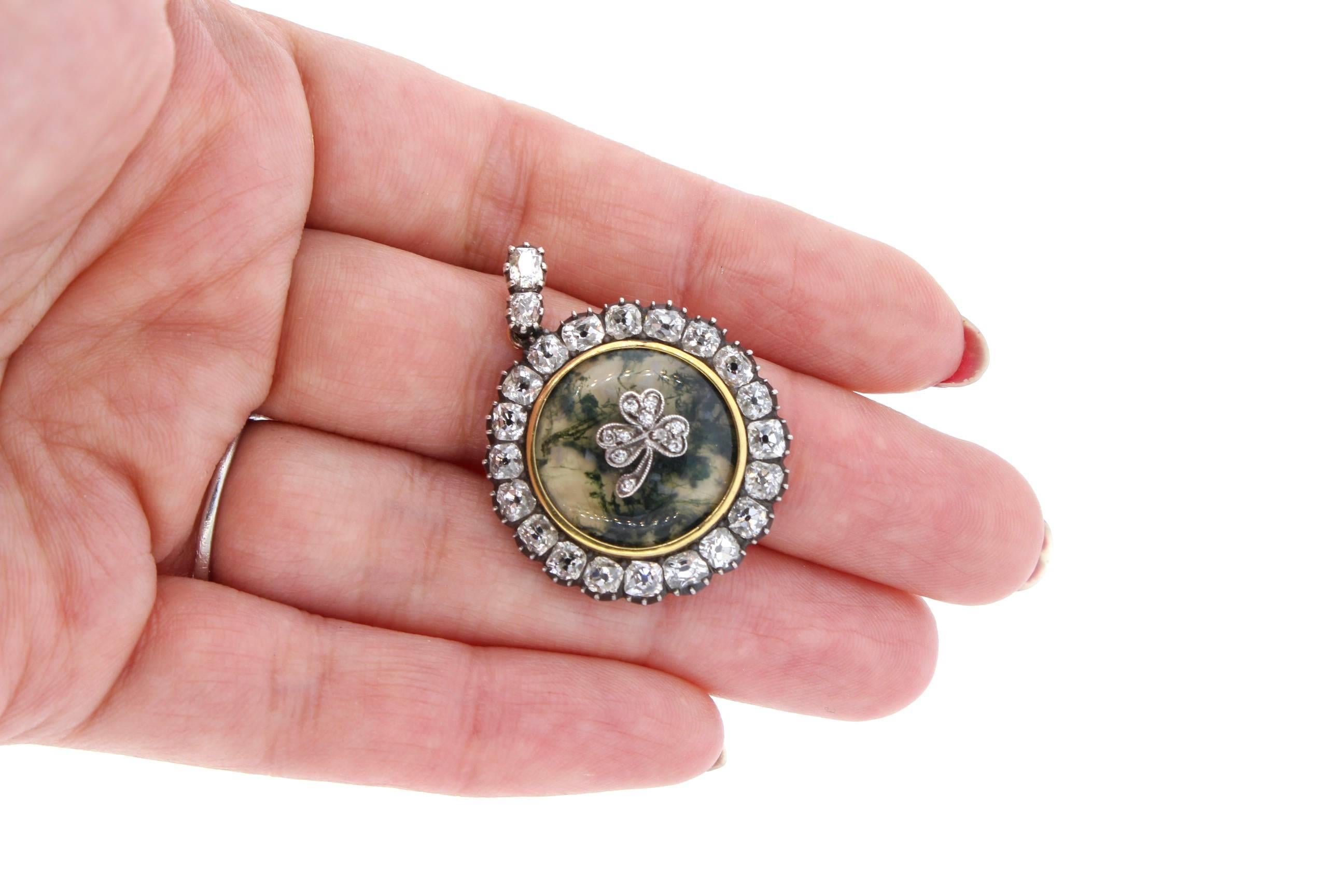 A charming pendant ready to suspend from a necklace centering on a round dendritic agate set with a three leaf platinum clover and diamonds.  The agate is surrounded by old mine cut diamonds and two diamonds are on the pendant bail.  There are 20