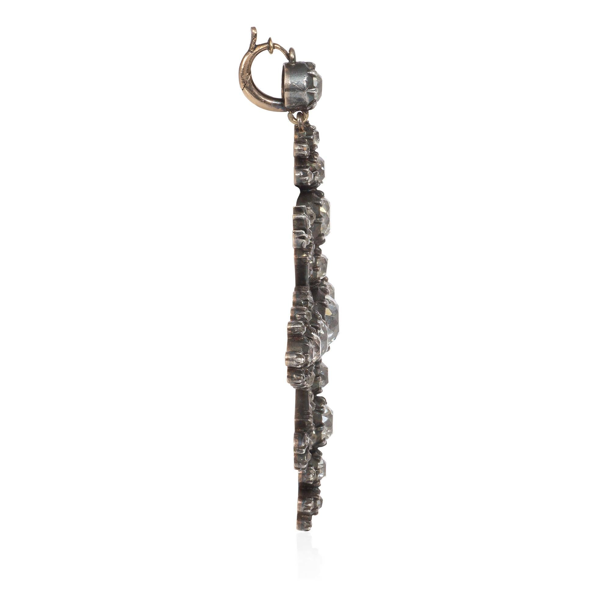 An antique Victorian period diamond pendant in silver-topped gold, set with old mine cut diamonds in the form of a starburst with torchière motifs on the diagonal axes, in sterling silver and 18k.  Atw diamonds 6.00 cts.  Pairs equally well with a