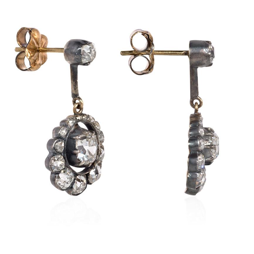 A pair of antique silver-topped gold earrings comprised of articulated cushion-cut diamond pendants in scalloped surrounds with solitaire surmounts, in 18K and sterling silver.  Atw 2.00 ct. old mine cut diamonds