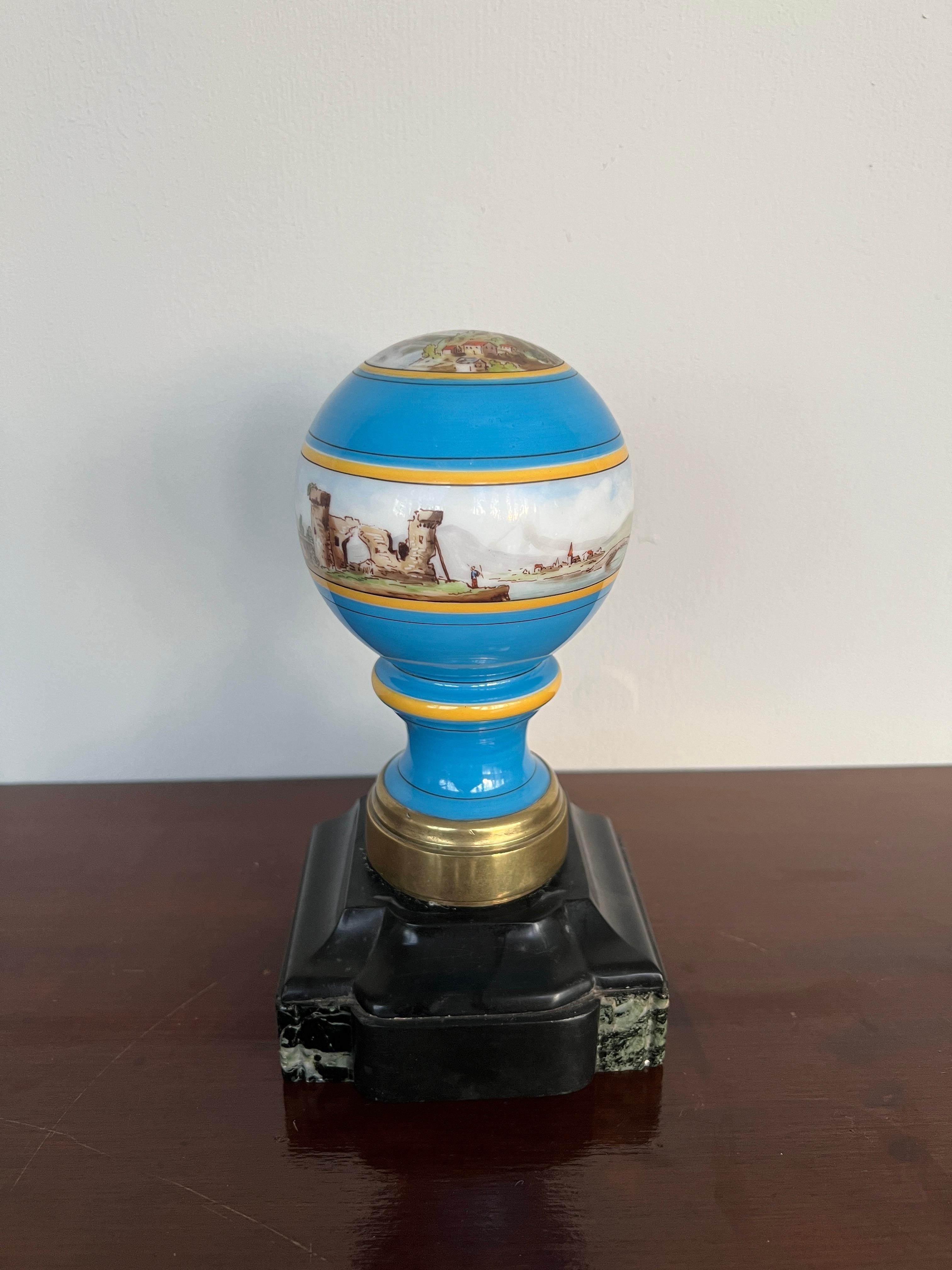 French, late 19th to early 20th century.

An antique Grand Tour era newel post finial in blue opaline with a hand painted scenic view to the top and exterior. The bottom has a bronze base cap and mounted to a piece of black marble. 
Note: The marble
