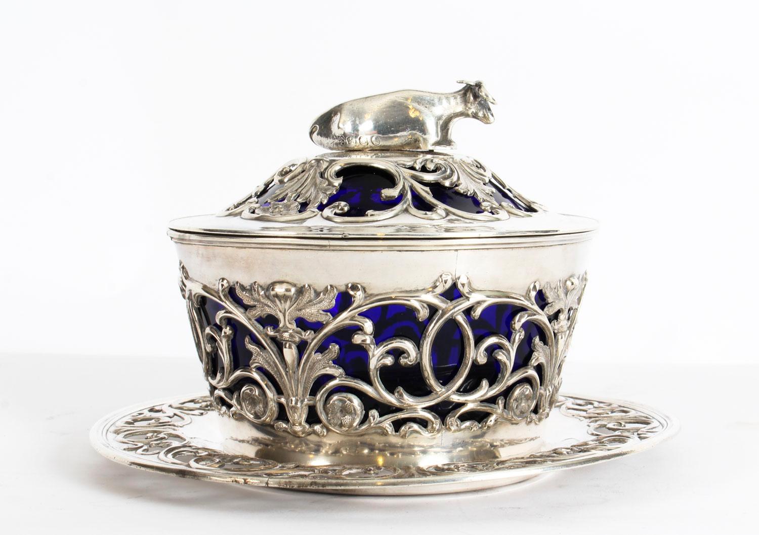 This is a fine antique English Old Sheffield silver plated and Bristol Blue glass lined butter dish, on stand, circa 1820 in date.

The lift up lid with a reclining cow decoration and features pierced decoration with the blue glass liner showing
