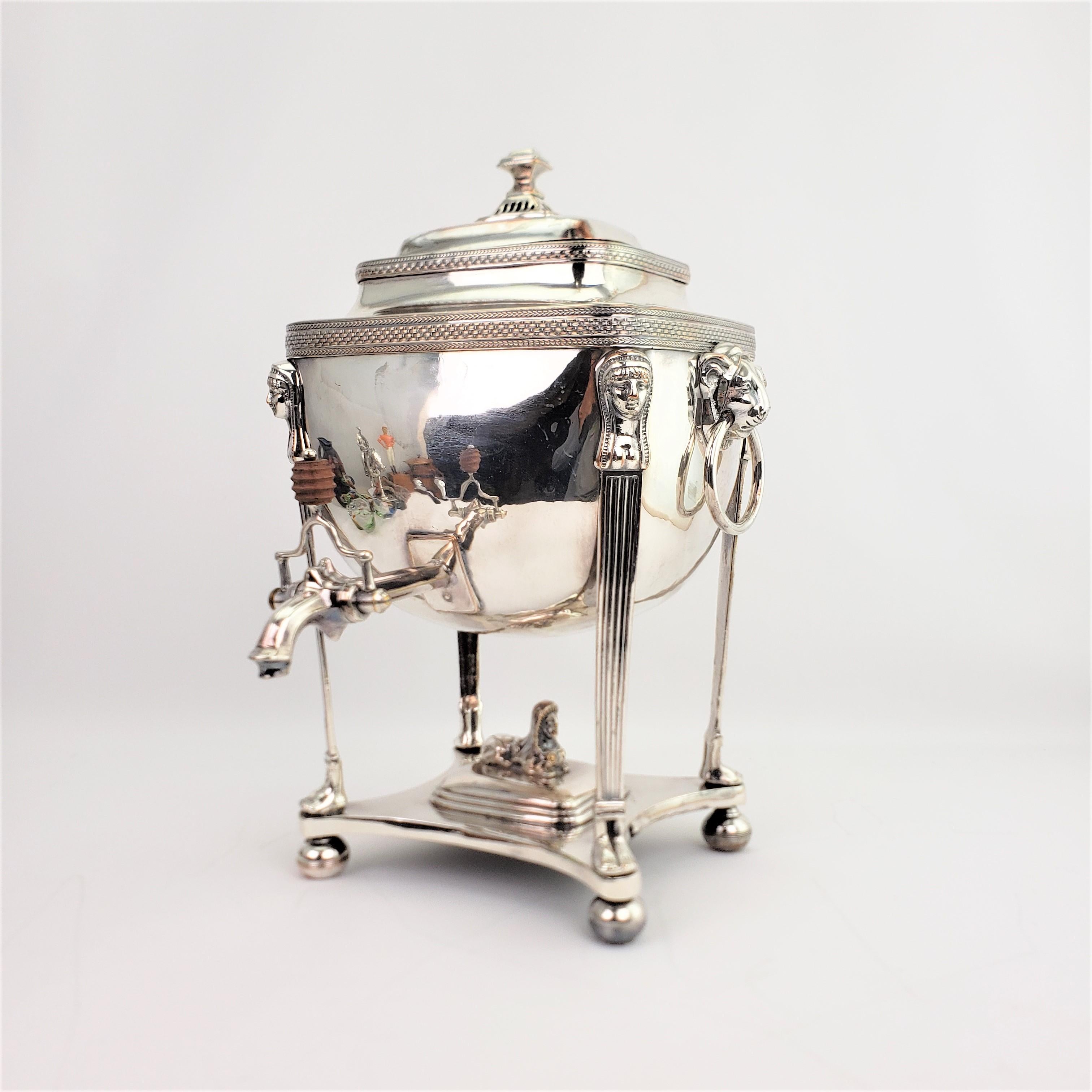 This antique silver plated hot water server is unsigned, but believed to have been made in England in approximately 1820 in the Egyptian Revival style. The server is done in an early Sheffield plate and features lion mounts on either side which