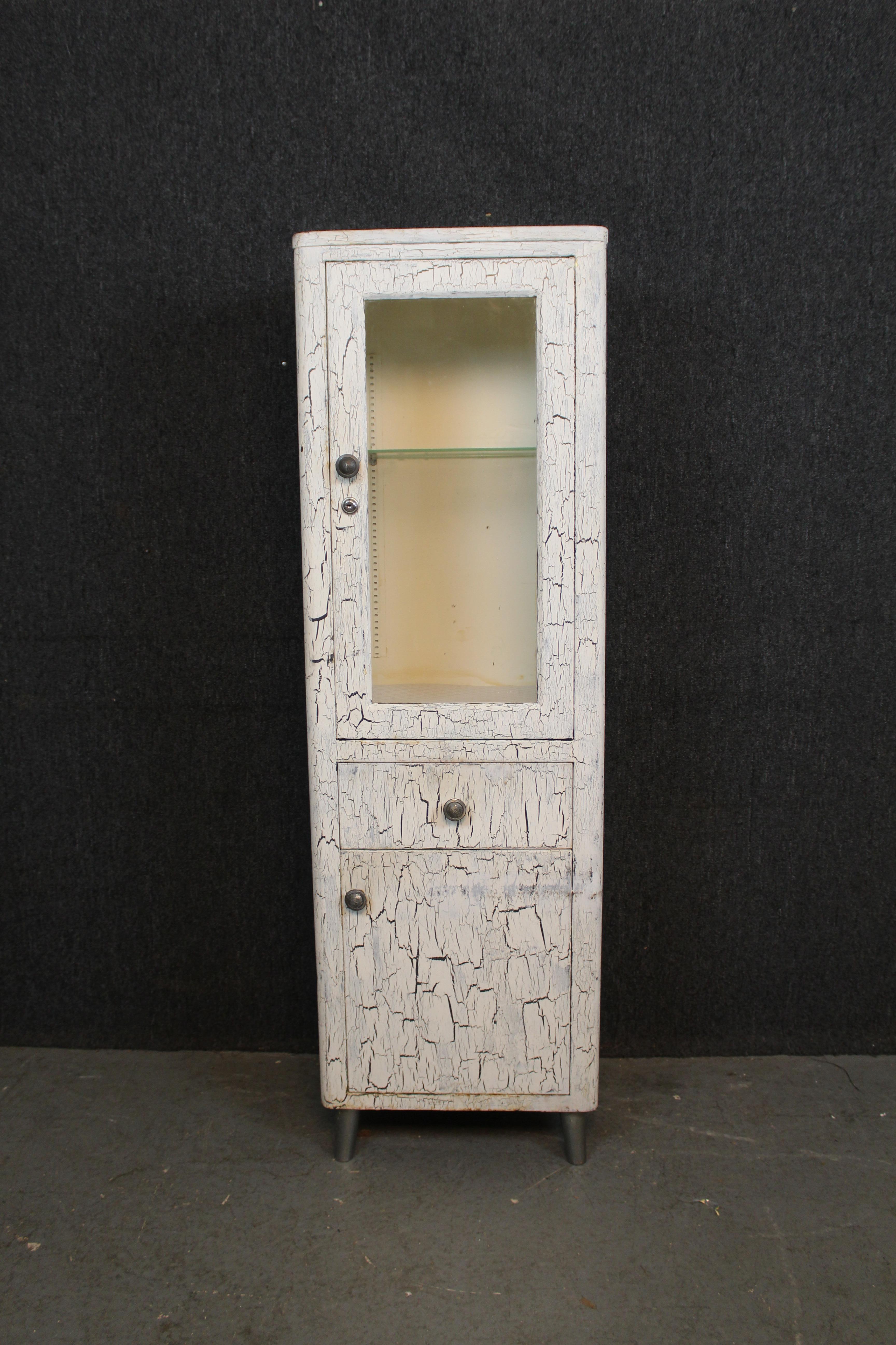 Don't miss out on this truly one of a kind antique industrial metal medical cabinet! Fully painted in a distressed white finish, giving it a fantastically unique, almost elephant-like appearance. Packed in a tidy 20
