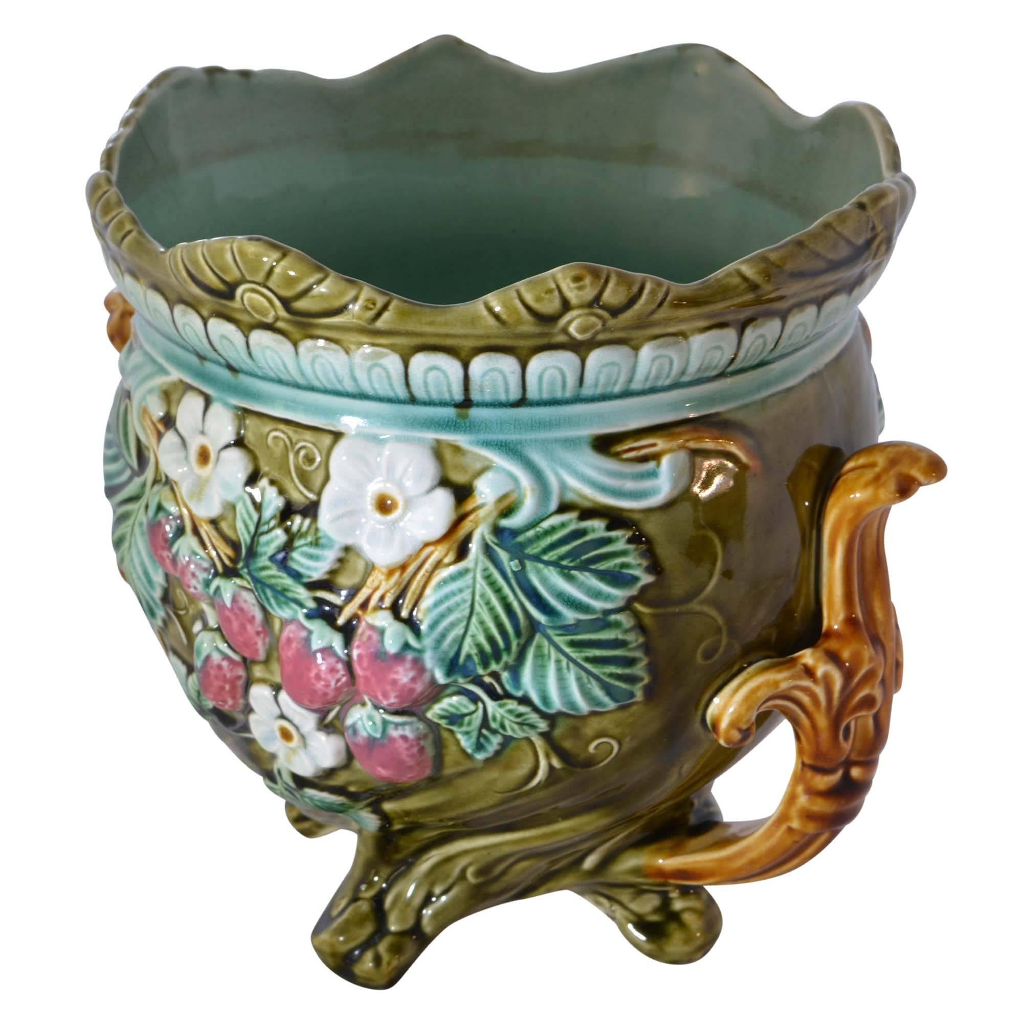 A colorful antique Onnaing French Majolica jardinière is in matching style to the other jardinière. This antique jardinière has a wavy flared rim and a raised floral design on the side with strawberry shaped accents. There is a teal finish inside of