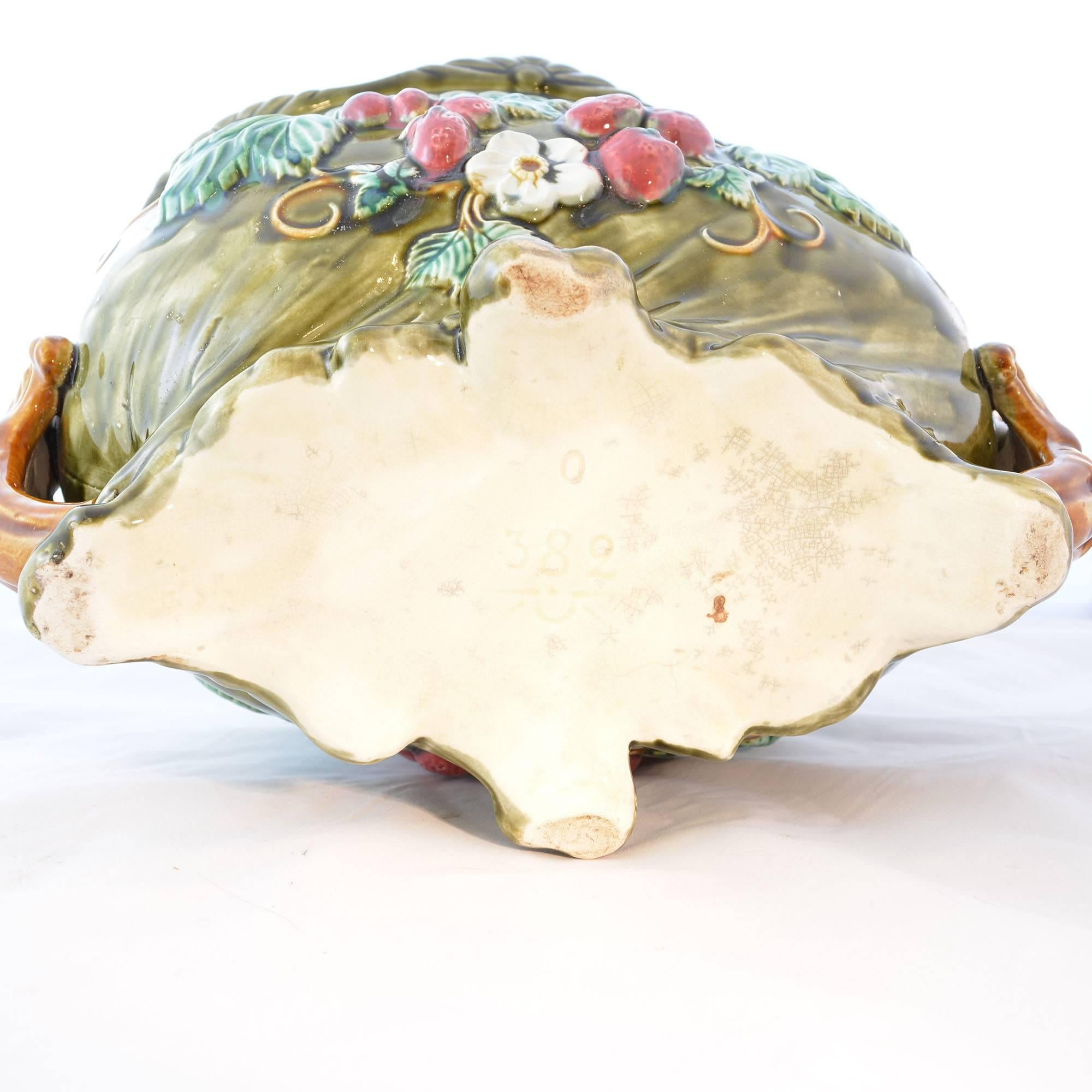A colorful antique Onnaing French Majolica jardinière. The jardinière is oblong with a wavy flared rim, and a raised floral design on the side with strawberry shaped accents. There is a teal finish inside of the jardinière and a green glaze on the