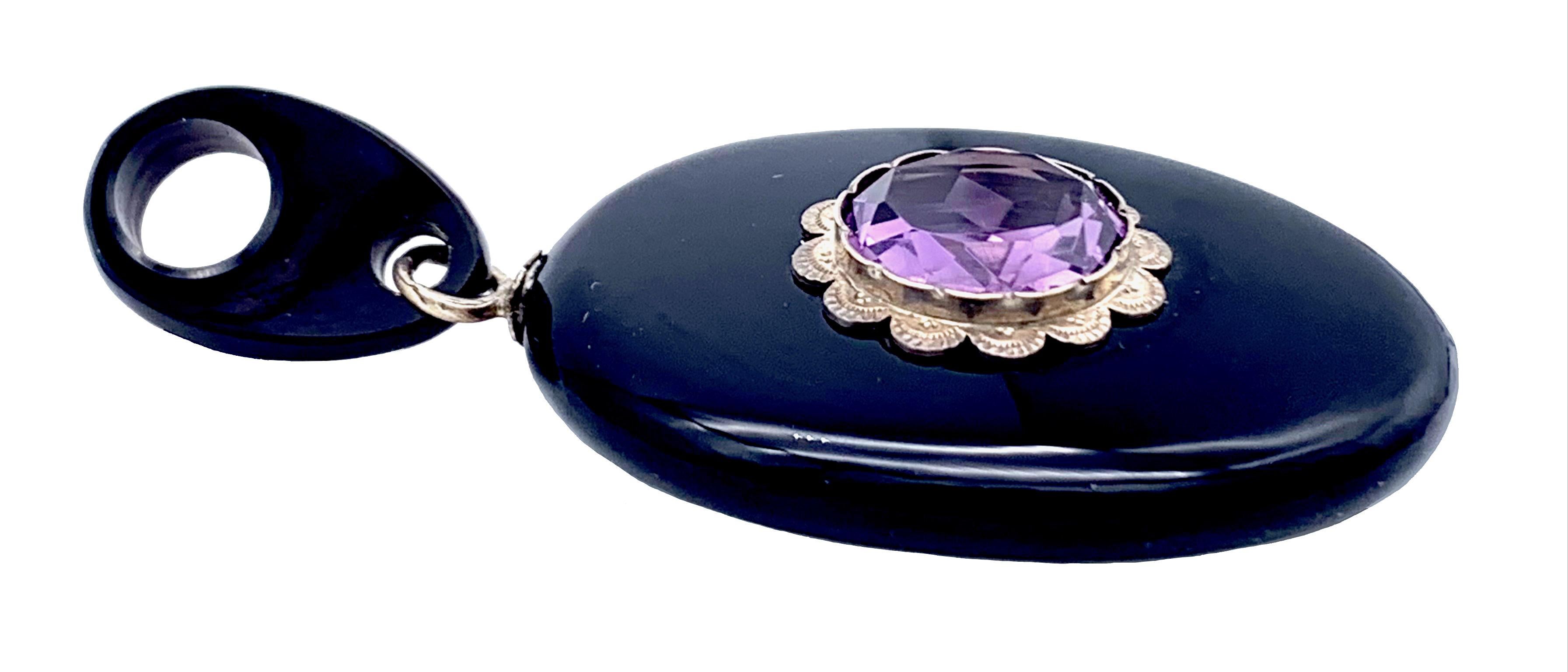 This elegant and onyx locket is decorated with an amethyst mounted in a finely engraved silver setting.