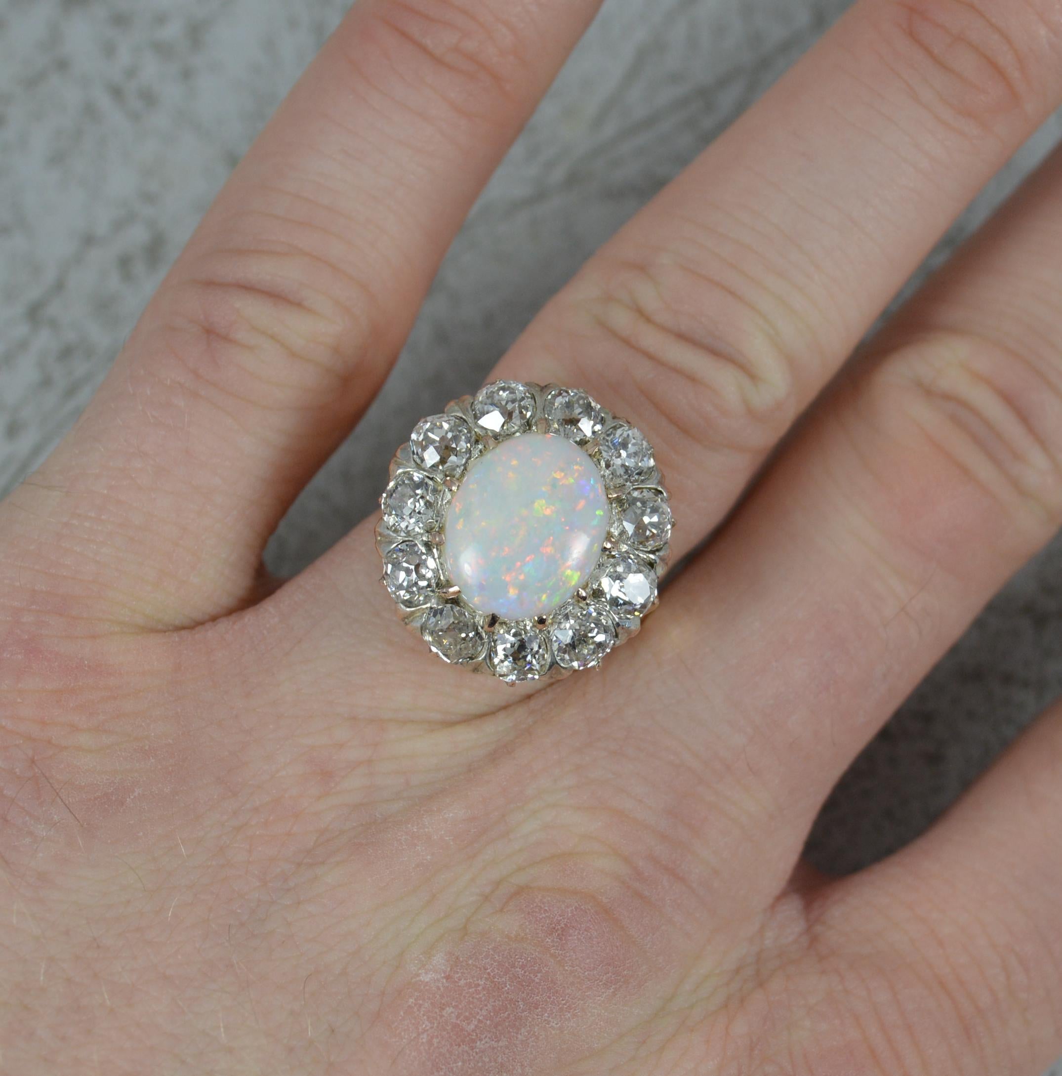 A superb Opal and Diamond cluster ring.
Solid 18 carat gold example.
Designed with an oval shaped opal to centre, 10mm x 12mm approx. A creamy undertone with sparks of all colours.
Surrounding are eleven natural old mine cut diamonds, approx 3.00