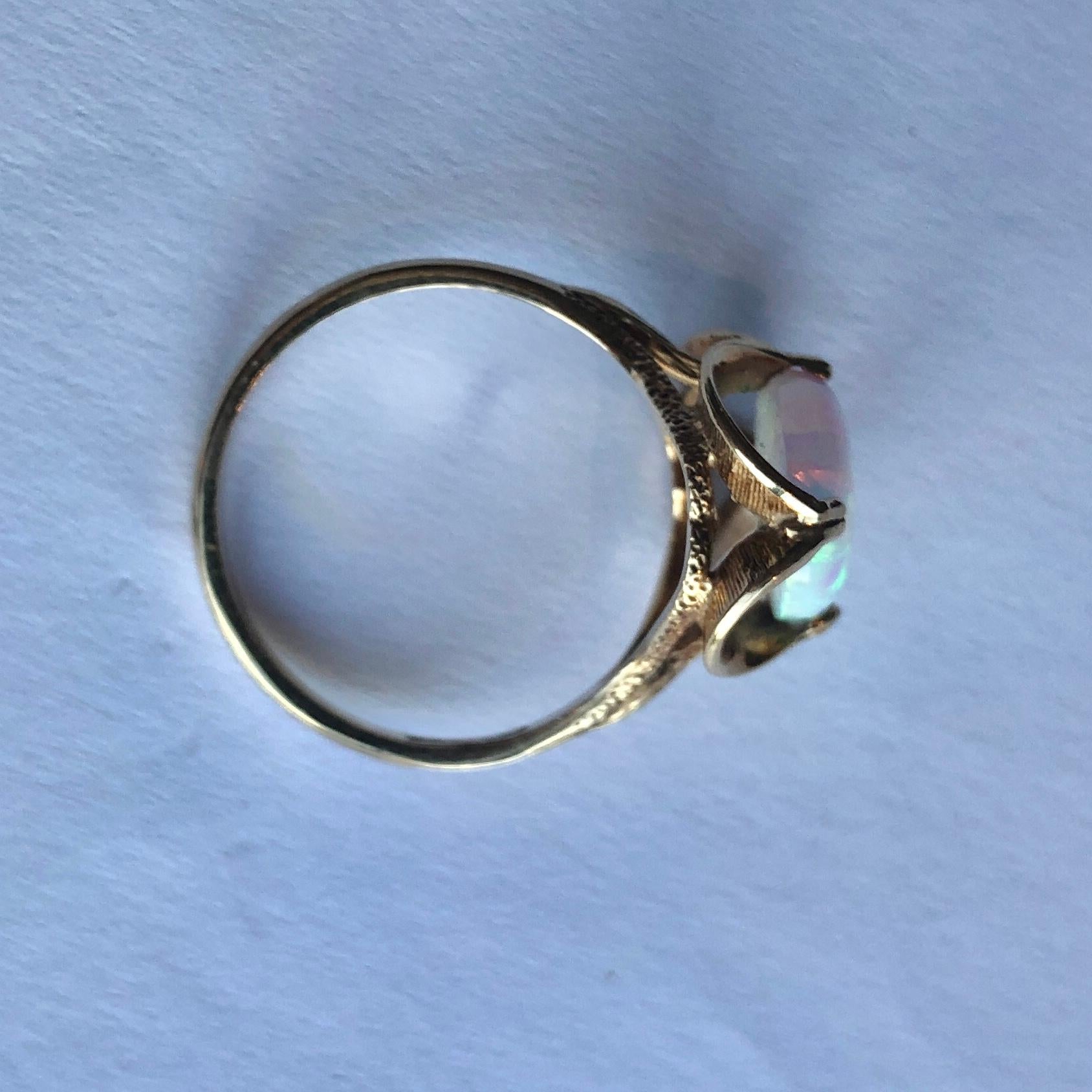 Ein wunderschöner, farbenprächtiger Opal sitzt in einer wunderschönen, gewellten Fassung. Der Ring ist aus 9-karätigem Gold modelliert und hat feine Gravuren auf der Galerie und den Schultern. Der Opal misst etwa 4ct. 

Ringgröße: R 1/2 oder 9
