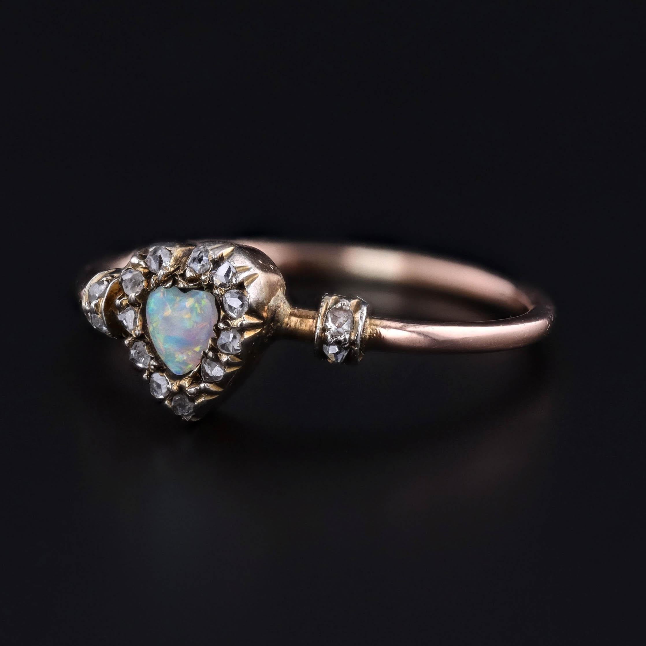 Ein antiker Ring mit einem herzförmigen Opal in einem Halo aus Diamanten, gefasst in einer Platinlegierung, die mit 18 Karat Gold überzogen ist.

Das Gesicht des Rings misst 0,3 Zoll durch 0,2 Zoll breit und ist in gutem Zustand. Es ist eine Größe