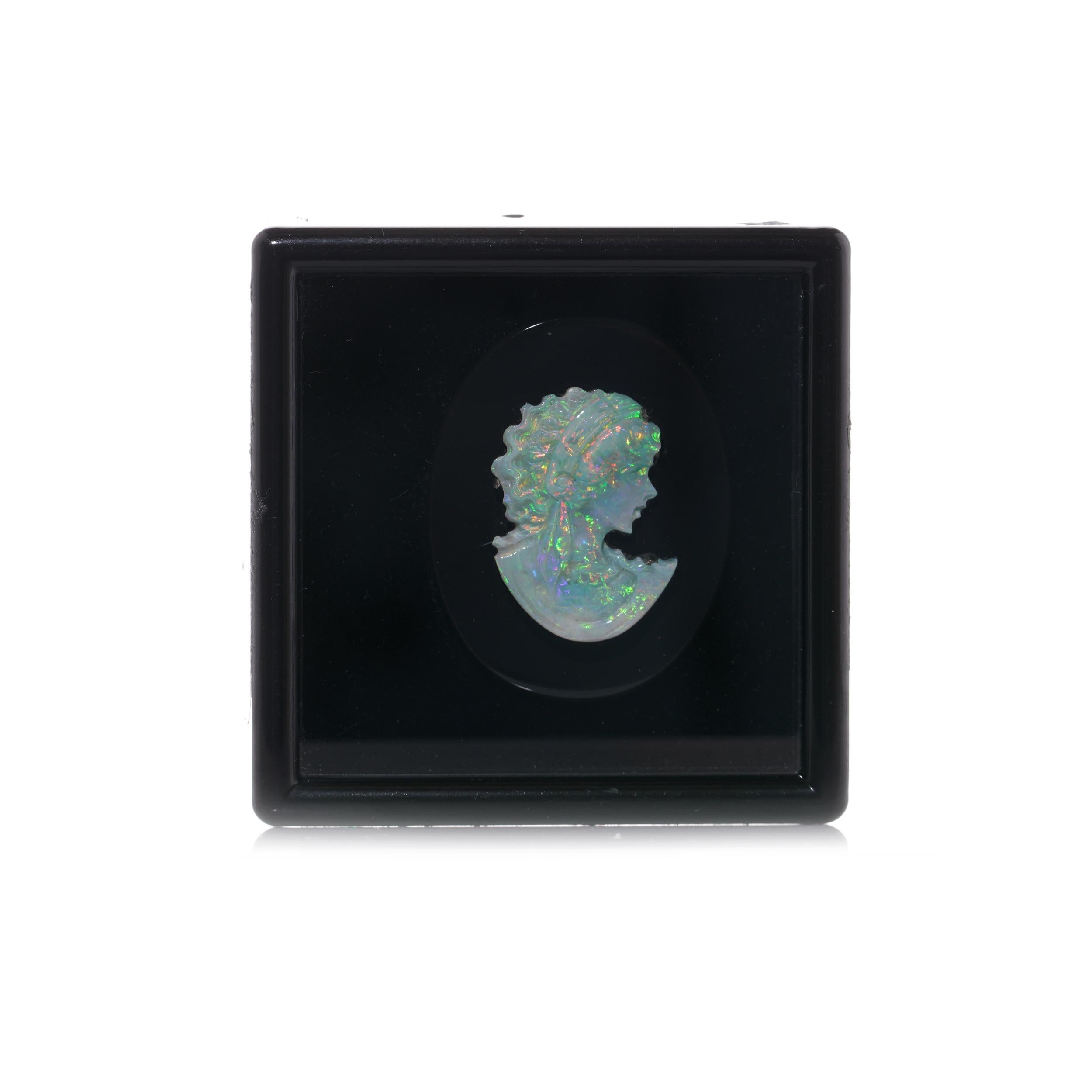 Antique opal carving cameo mounted on the onyx plaque. 
The plaque features an intricately carved opal cameo portraying the head and shoulders of a young lady. 

The dimensions:
Opal cameo size: 21 mm x 16mm
Onyx plaque size: 31 mm x 25 mm
 Weight:
