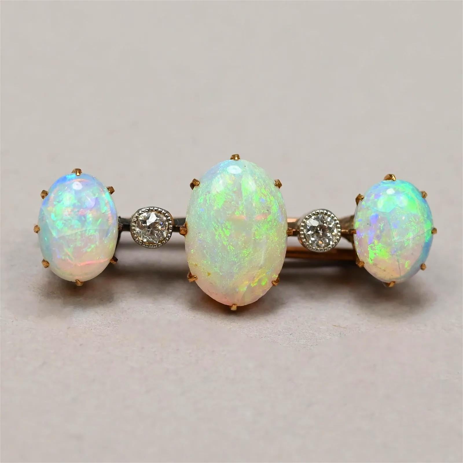 This luxurious antique Edwardian pin brooch circa 1880-1917 makes an exquisite addition to your collection. Boasting three prong-set oval opals cabochons with a gorgeous blue, violet, and peach play-of-color and a green flash, and two sparking