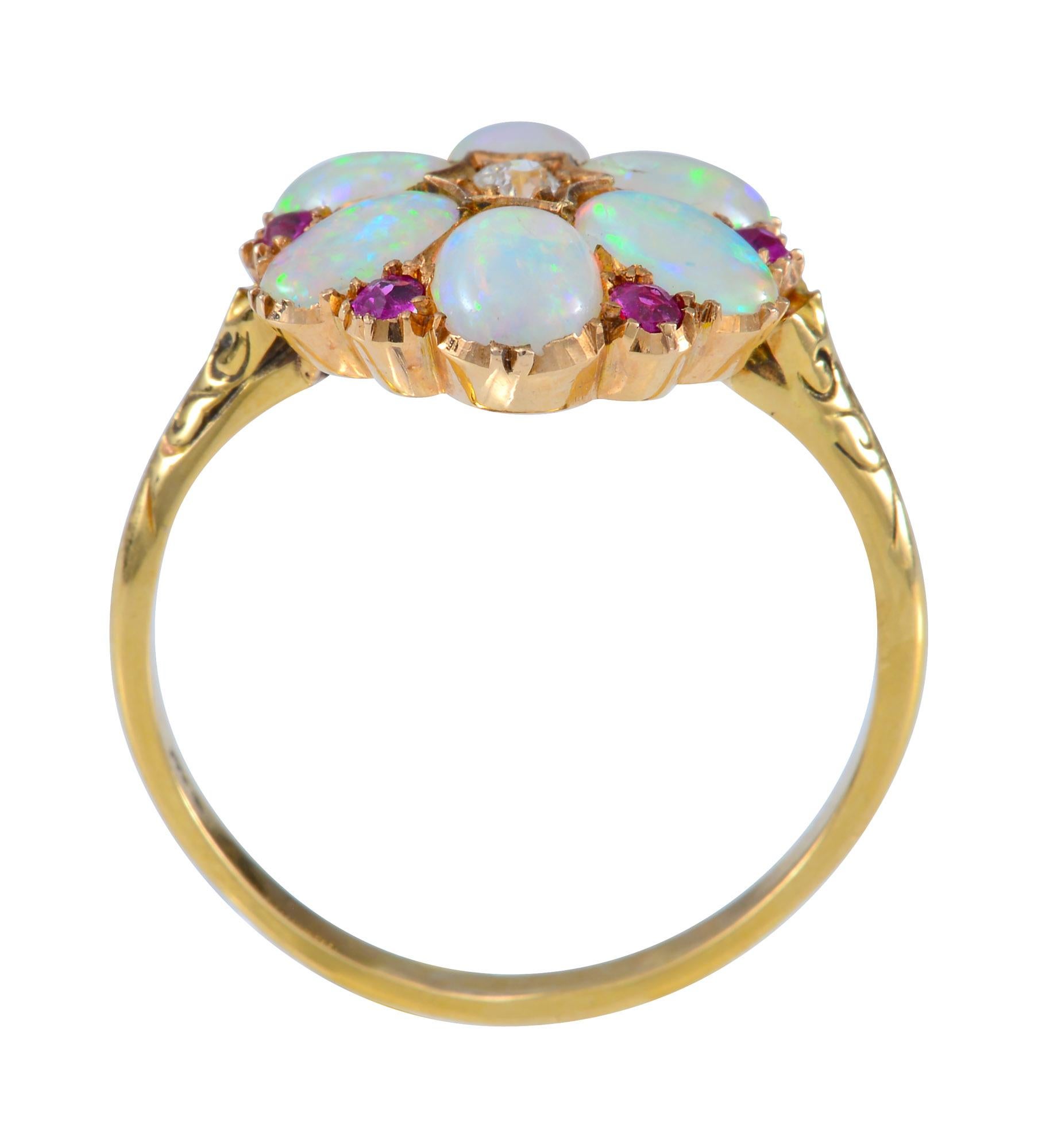 This Antique Opal , Ruby and Diamond Ring in 18ct yellow gold features 6 oval crystal opals of approximately 6mm by 4mm indispersed with 6 old cut rubies of approximately 1.5mm in diameter with a total weight of 0.12 cts. The centre of the ring is