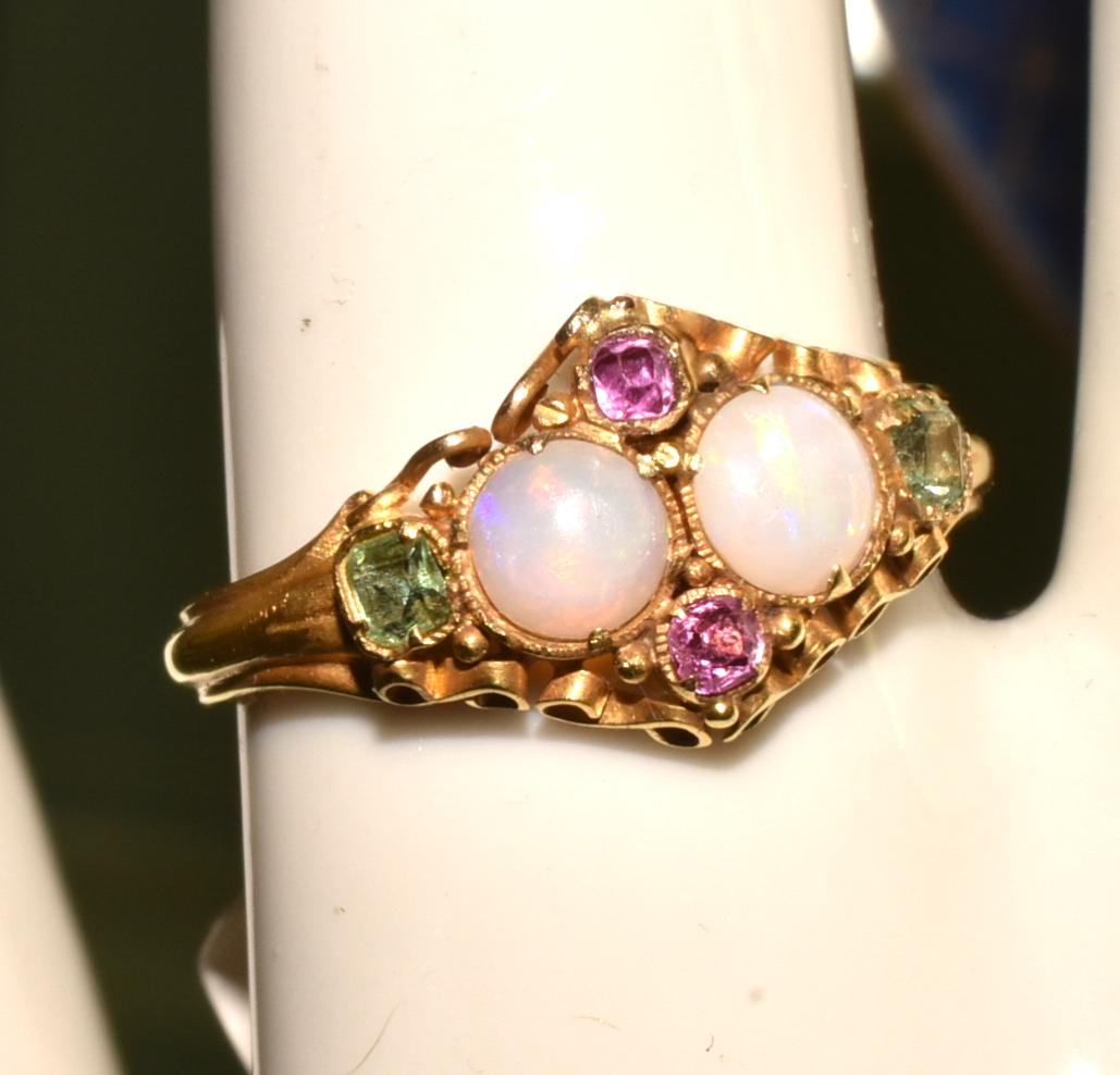 2 opals form the centerpiece of this lovely natural opal, ruby and peridot 15k gold ring, hallmarked Birmingham and dating to 1866. Curlicues, whorls and incising add interest to this sentimental Victorian ring. Opals were among Queen Victoria's