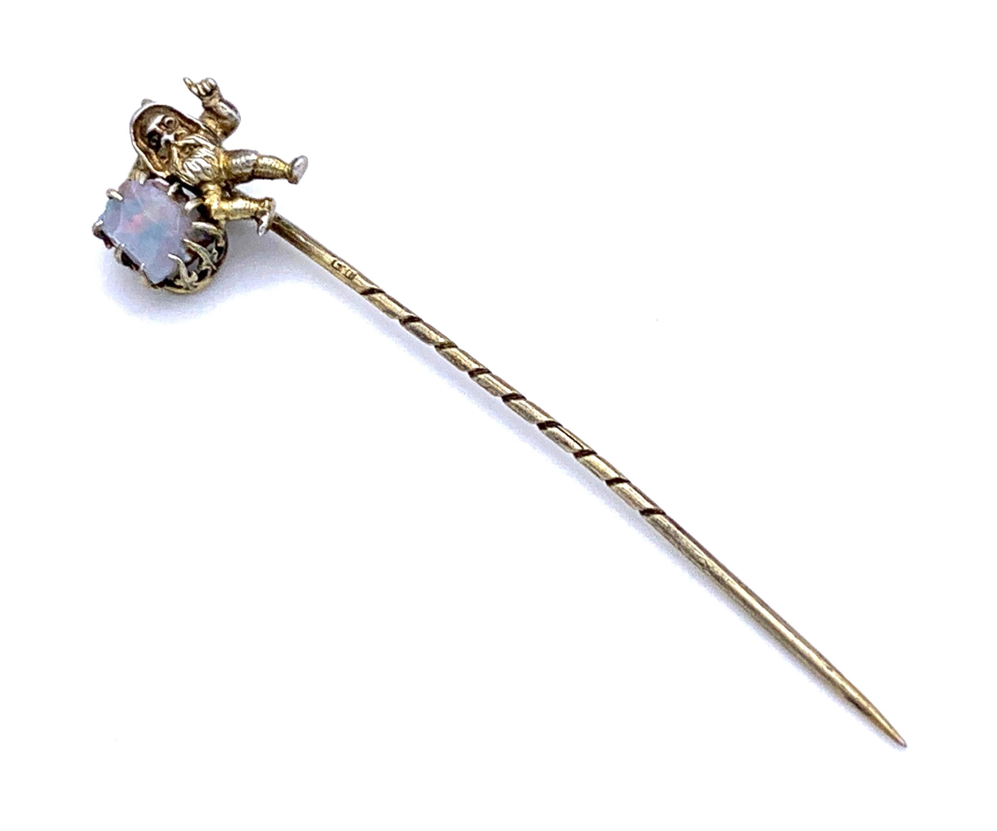This unusual stickpin features a bearded gnome with a hood. Under his right arm he is holdig an opal and he raises the finger of his left hand. 