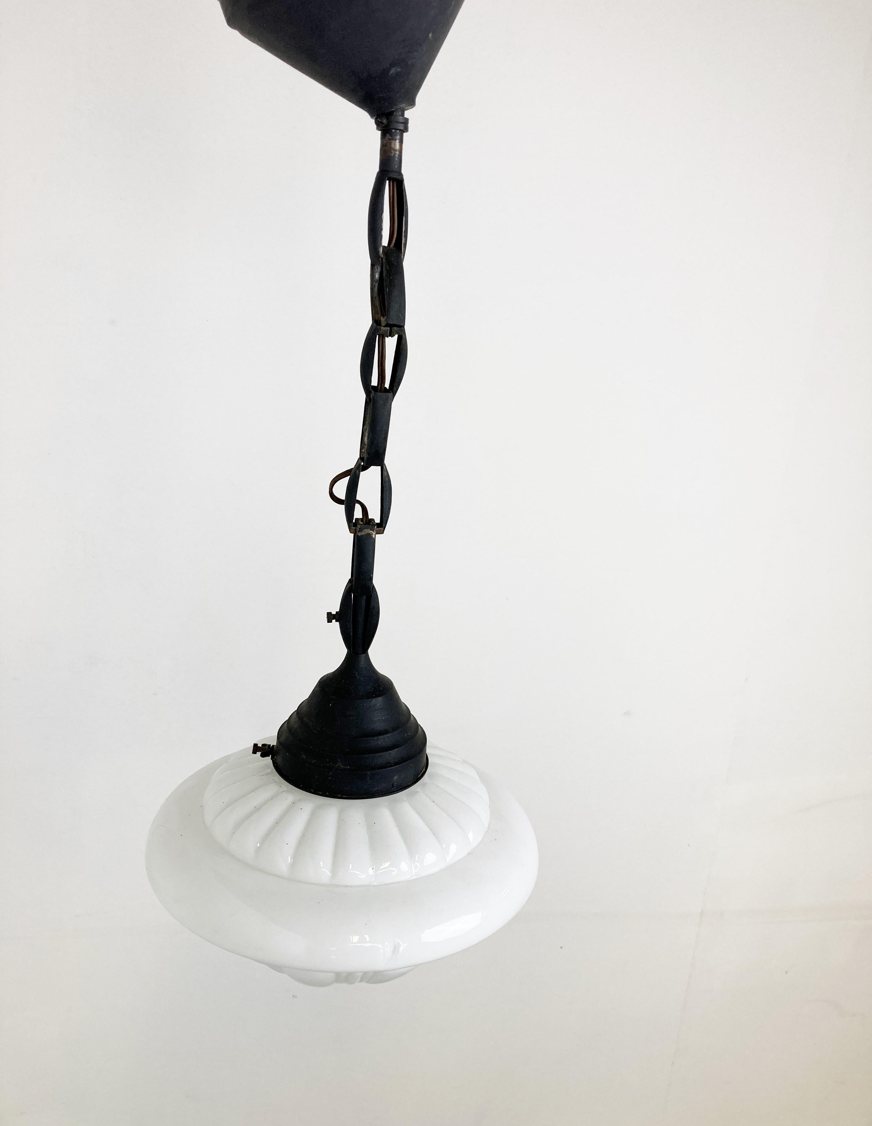 Suspension art déco antique pour couloir.

Cette lampe est très typique de l'époque art déco et était largement utilisée pour être accrochée dans les couloirs, les bureaux ou les lieux publics plus importants.

La lampe est dotée d'une chaîne en
