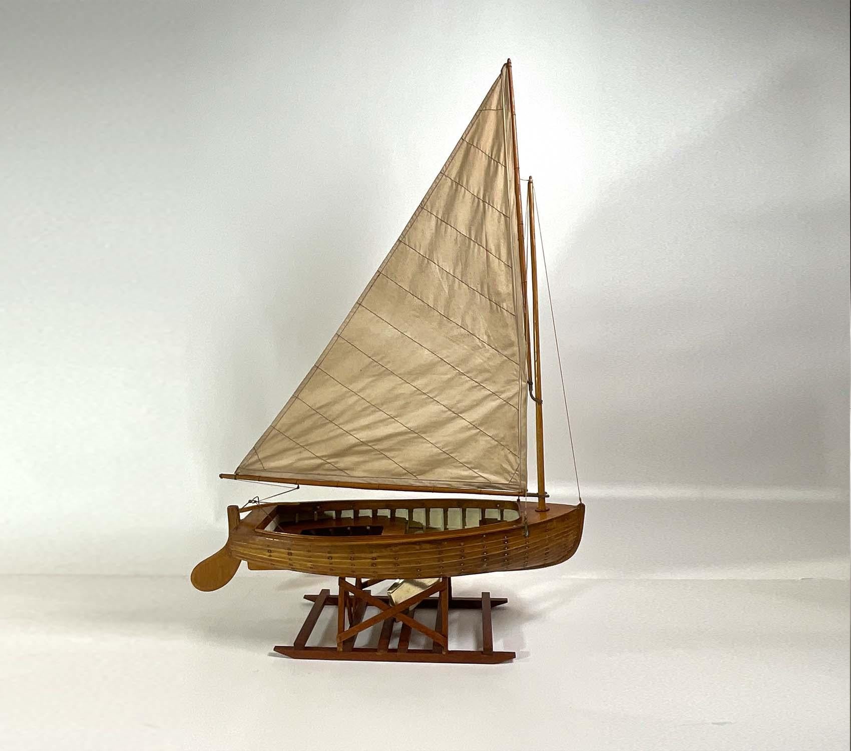 Exceptional boat model of a Lapstrake sloop. The hull is fitted with ribs, dropped brass centerboard, floorboards, rudder with tiller. Expertly crafted. Set onto a quality cradle mount. Circa 1935. Top notch craftsmanship. Look closely and zoom in