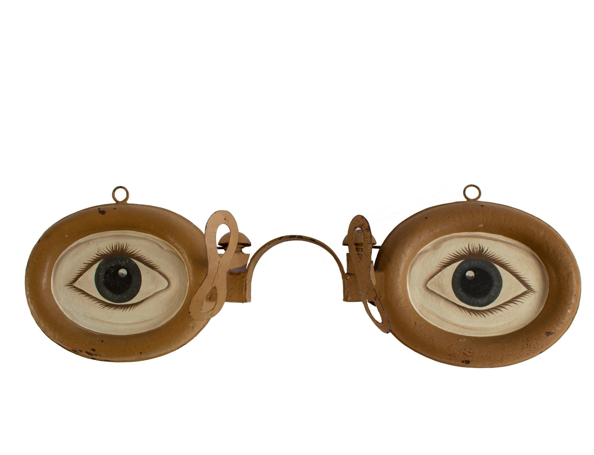 Antique hanging advertising sign for an optician, circa 1920-1930. Double sided big cast zinc glasses with four hand painted eyes on original adjustable iron wall bracket. Collectable item for a wall decoration, interior design, curiosity. A nice