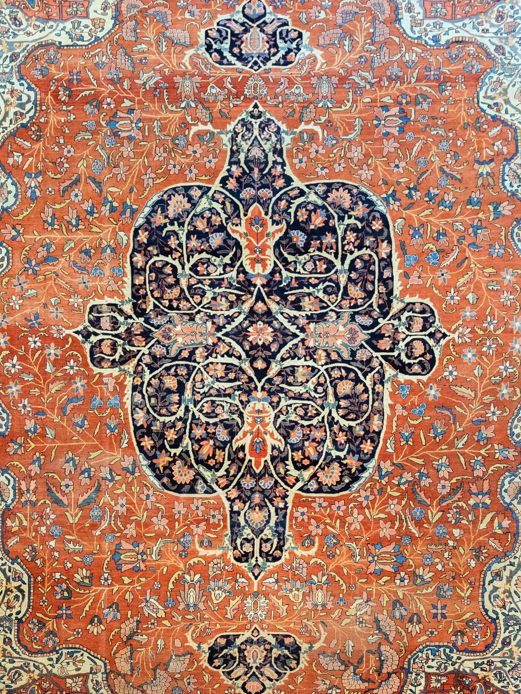 With a warm orange background and a deep indigo medallion, this hand knotted antique Farahan carpet measures 10’5” x 14’1”. Woven circa 1890 in a traditional Persian weave, the Classic Farahan design illustrates a blooming flower garden decorated