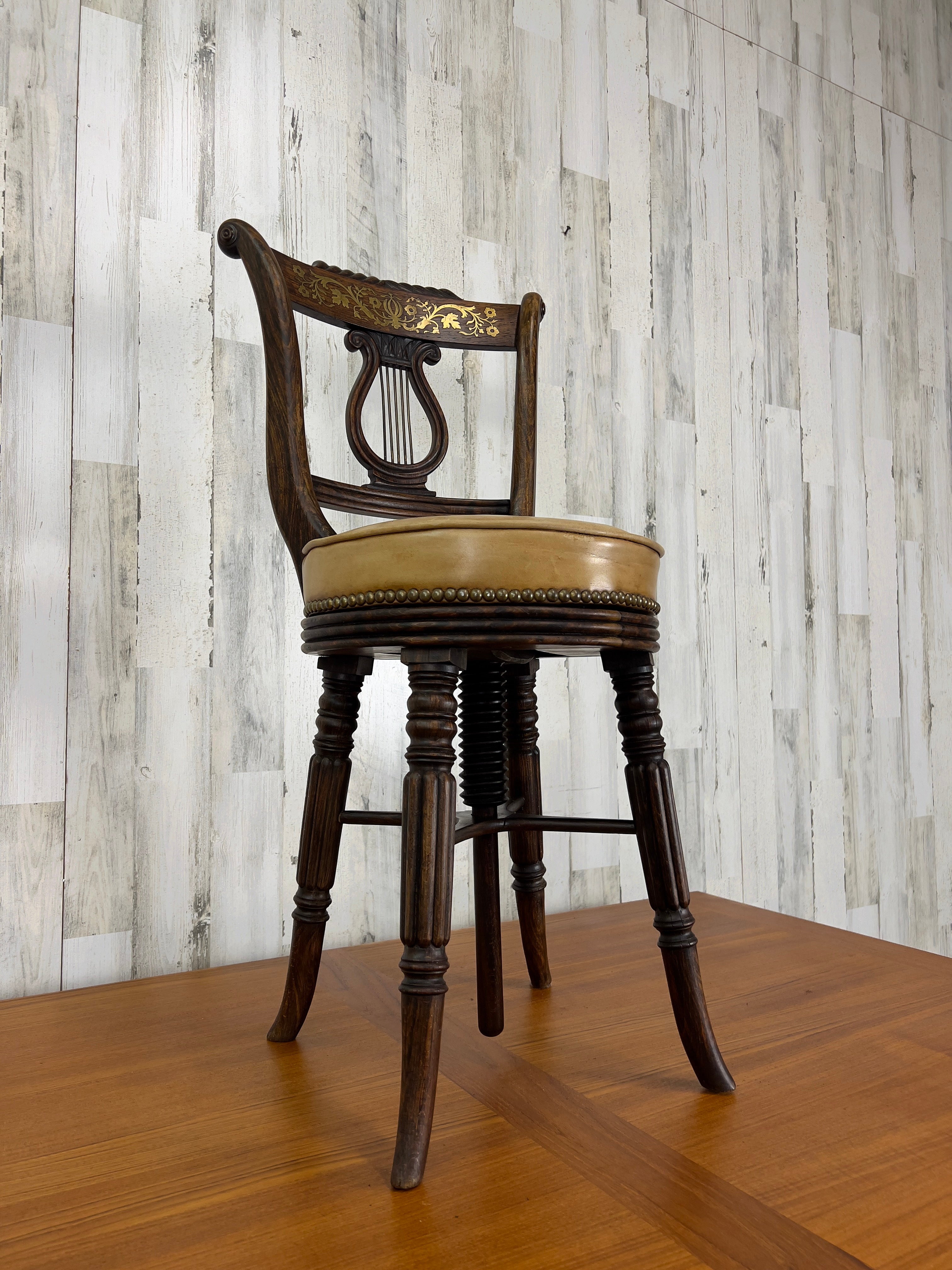 Chaise musicale en bois dur fabriquée à la main avec incrustation de laiton sur le dossier de la chaise et siège fileté pour le réglage de la hauteur. Le siège en cuir a été remplacé à un moment donné.
Cette chaise était probablement utilisée pour