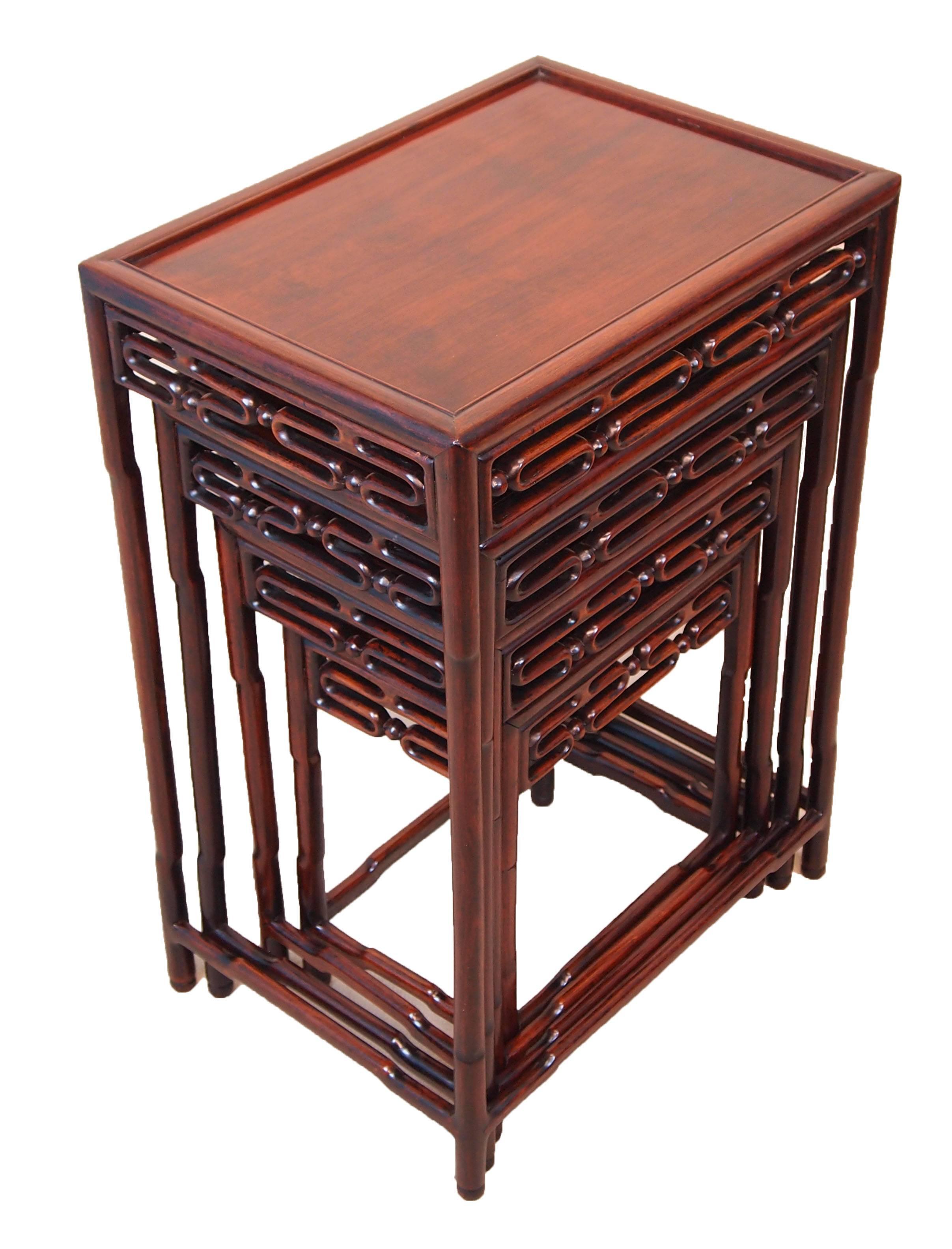 A very attractive and good quality nest of four oriental
hardwood coffee tables having superbly figured panelled
tops and pierced carving to frieze.