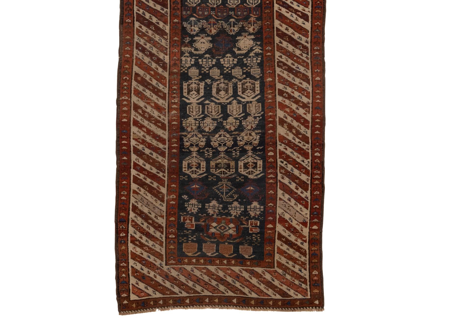 This antique Kurdish runner dating back to the 1900s is truly impressive. The piece boasts a breathtaking design that is utterly dominated by striking geometric patterns set against a rich blue and red field. Adding to its charm are a number of