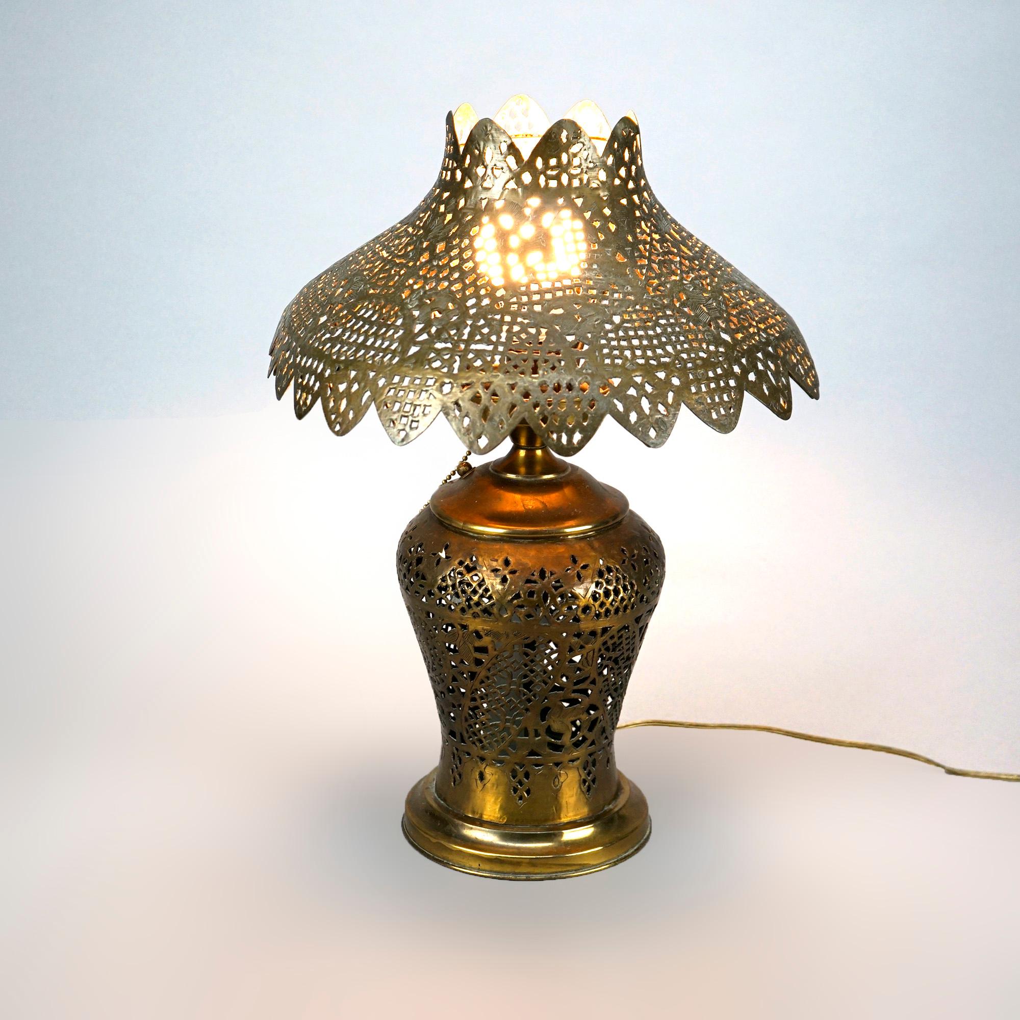 An antique Orientalist Damascus table lamp offers brass construction with reticulated shade and single socket base, wired for US electricity, c1920

Measures- 17''H x 13''W x 13''D.