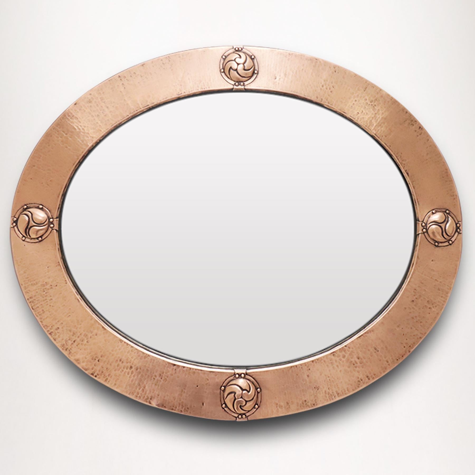 A superb and finely crafted original 1895 English Arts and Crafts period hammered copper oval mirror believed to be designed by Archibald Knox for Liberty & Co; the hammered copper bezel frame featuring copper cabochons depicting Celtic symbols of