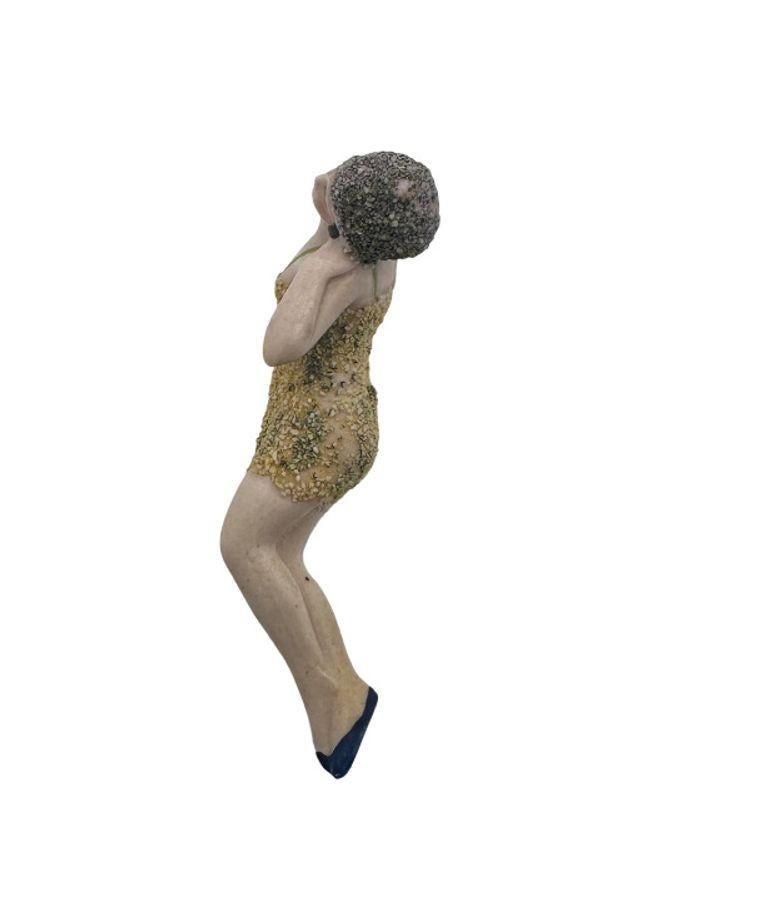 The Circa 1920 Hertwig Germany all-bisque bathing beauty flapper figurine is a small collectible item from the early 20th century.

It depicts a flapper-style woman wearing a low-cut green swimsuit with a grainy texture resembling sugar or