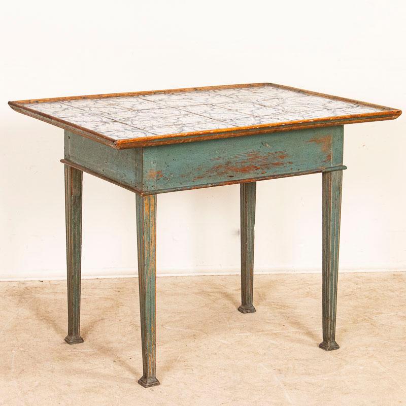 The original blue painted finish compliments the simple lines of the fluted tapered legs which carry upwards through the apron in this traditional Louis XVI side table from Sweden. The enchanting top is comprised of 35 individual antique blue and