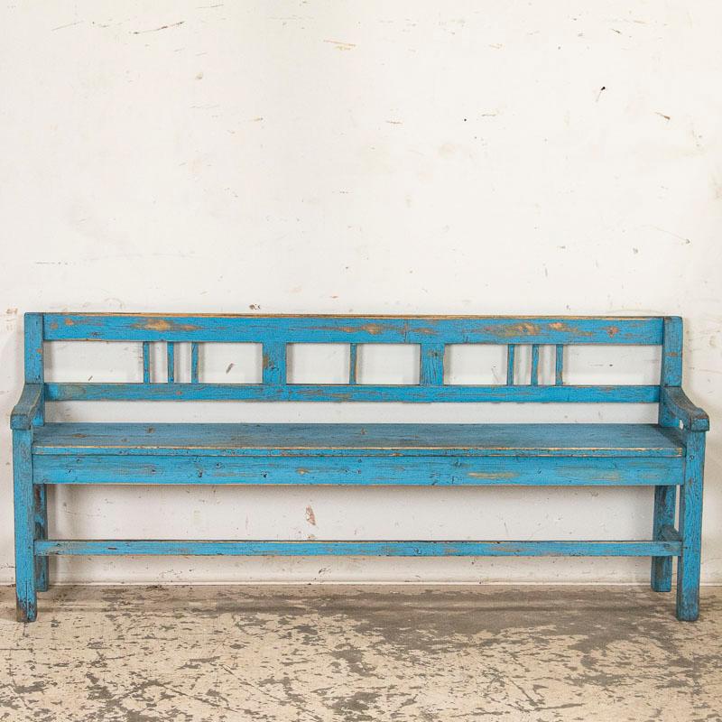 It is the worn and wonderful original blue painted finish that captures one's attention in this inviting bench. While the paint has clearly been distressed through years of use revealing the natural pine below, it creates the authentic vintage