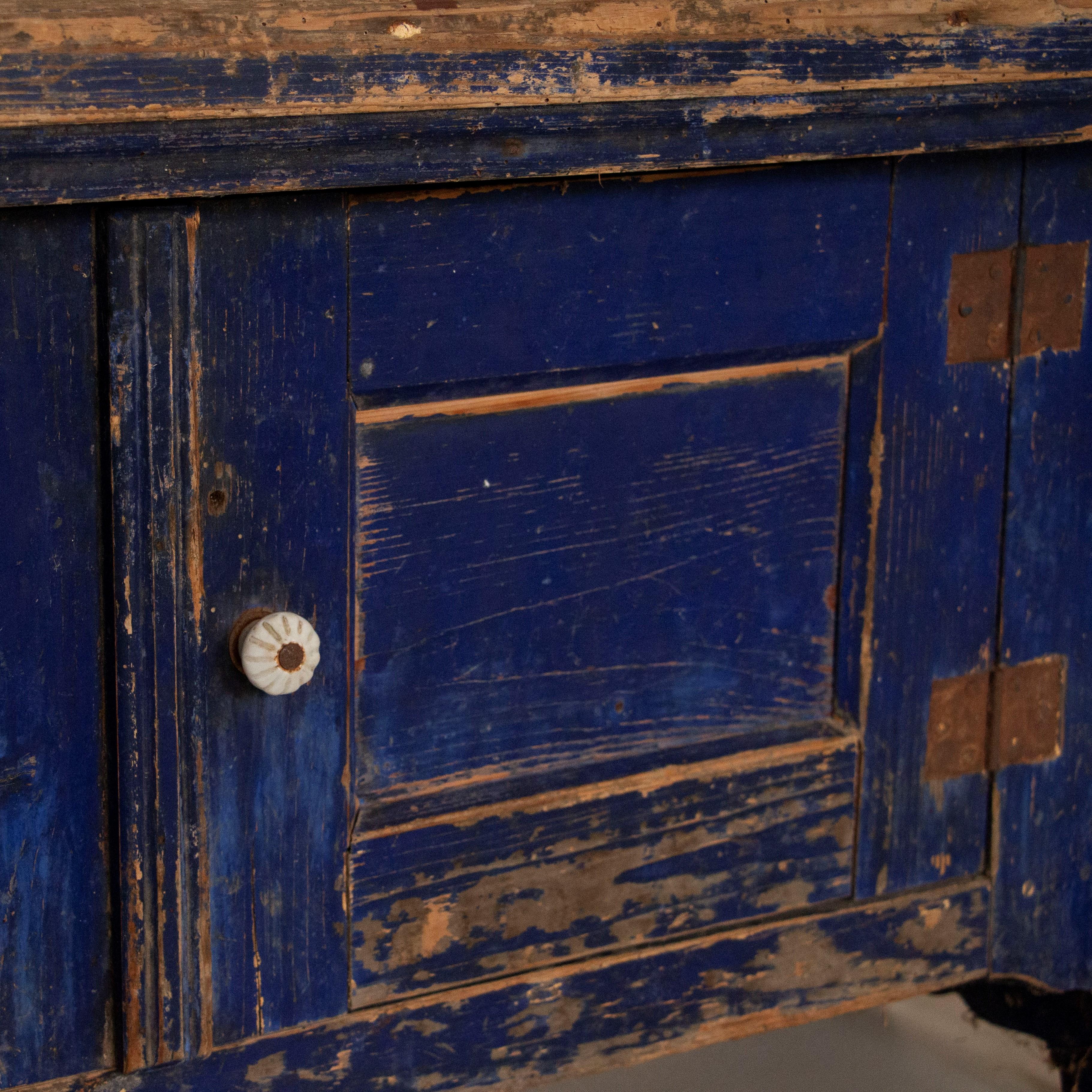 The eye-catching cobalt blue paint is all original in this long bench. While pine benches were a traditional element in country homes and farmhouses of Europe, this one is a special find due to the unique lower cabinet that create easy storage.