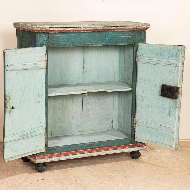 While you can frequently still find antique pine cabinets, it is difficult to find a sideboard with exceptional original folk art paint such as this one. The two panel doors are painted with a traditional pink flower motif against a lovely blue