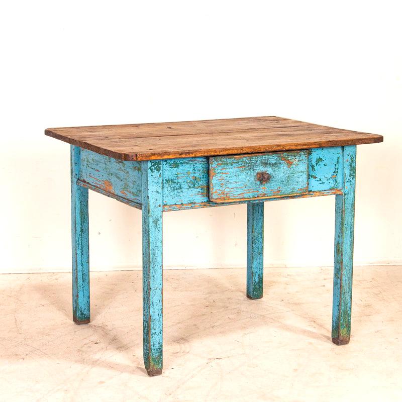 The charm of this cottage style table is in the simple details and rich patina of the distressed hard wood top and painted base. On the base, the warm natural pine is exposed where the original blue (and even some underlying green) paint has been