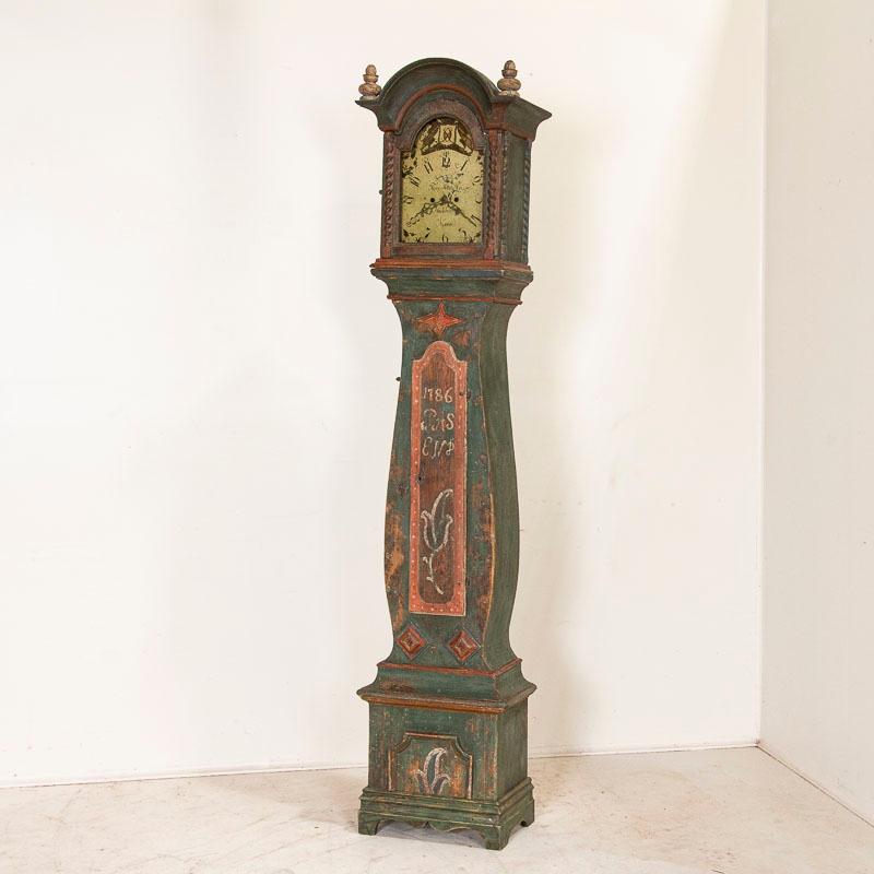 The graceful curves of this tall grandfather clock are what define the famous Mora clocks of Sweden. The impressive date of 1786 is clearly visible on the longcase while the original pale green paint (almost teal) and red trim has gently faded
