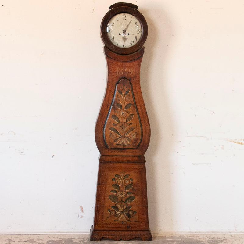 The lovely paint is all original on this Swedish Mora grandfather clock. The earth tones seen here were very traditional, with the background colors imitating a wood grain. The additional floral motif, sometimes referred to as rosemaling, add to the