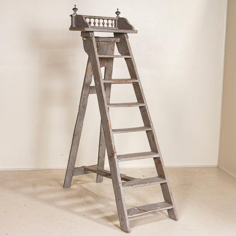 The wonderful worn gray paint is all original on this lovely library ladder from France. The top 8th rung acts as a small shelf if one cares to use it for display. The decorative finials add a special touch to the top as well. The first/lowest rung