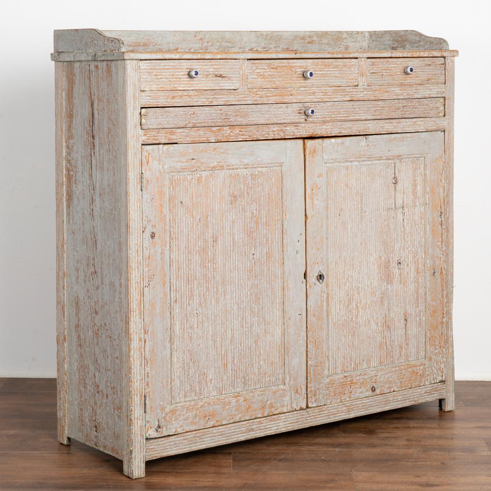 It is the original gray painted finish which has been scraped that brings out the warm patina of the pine in this lovely Gustavian sideboard or buffet from the Swedish countryside.
Three small drawers rest over one long narrow drawer which each
