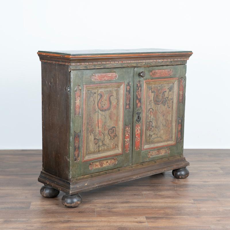 While you can frequently still find antique original painted trunks, it is difficult to find a sideboard with exceptional original folk art paint such as this one. The two panel doors are painted with a traditional floral motif against a soft green