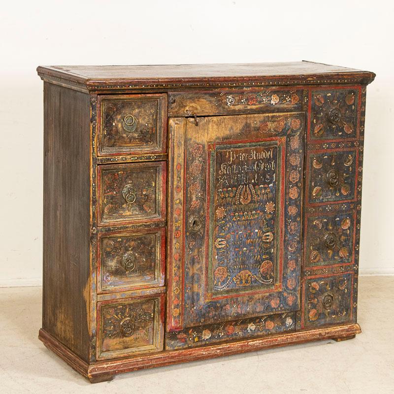 Delightful in every way, this sideboard still maintains its original highly decorative and colorful painted finish in traditional colors of red, blue, green and dark blue with flowers and flourishes throughout. Unique to this cupboard is the