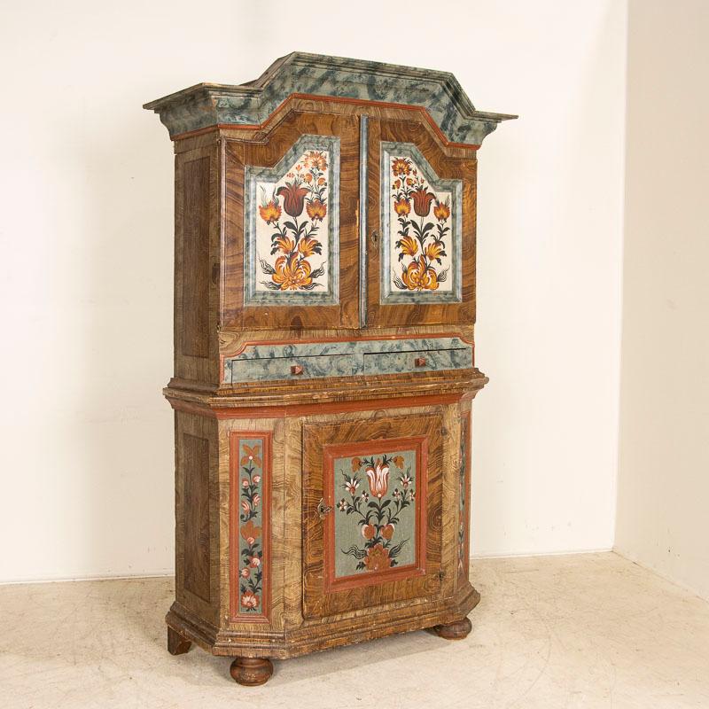 The gentle beauty of this Swedish three-door cabinet is found in the original paint reflecting traditional Swedish design with tulips, faux marbling and faux wood background. Notice the interior has contrasting seafoam green paint and the upper